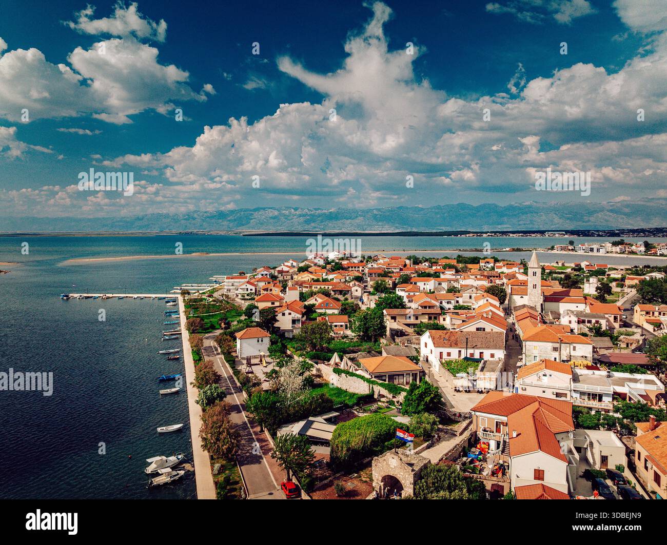 Vista aerea dell'affascinante città con i suoi tetti di tegole rosse annidati contro il tranquillo mare azzurro, un contrasto sorprendente sotto il vasto cielo blu, Nin, ZA Foto Stock