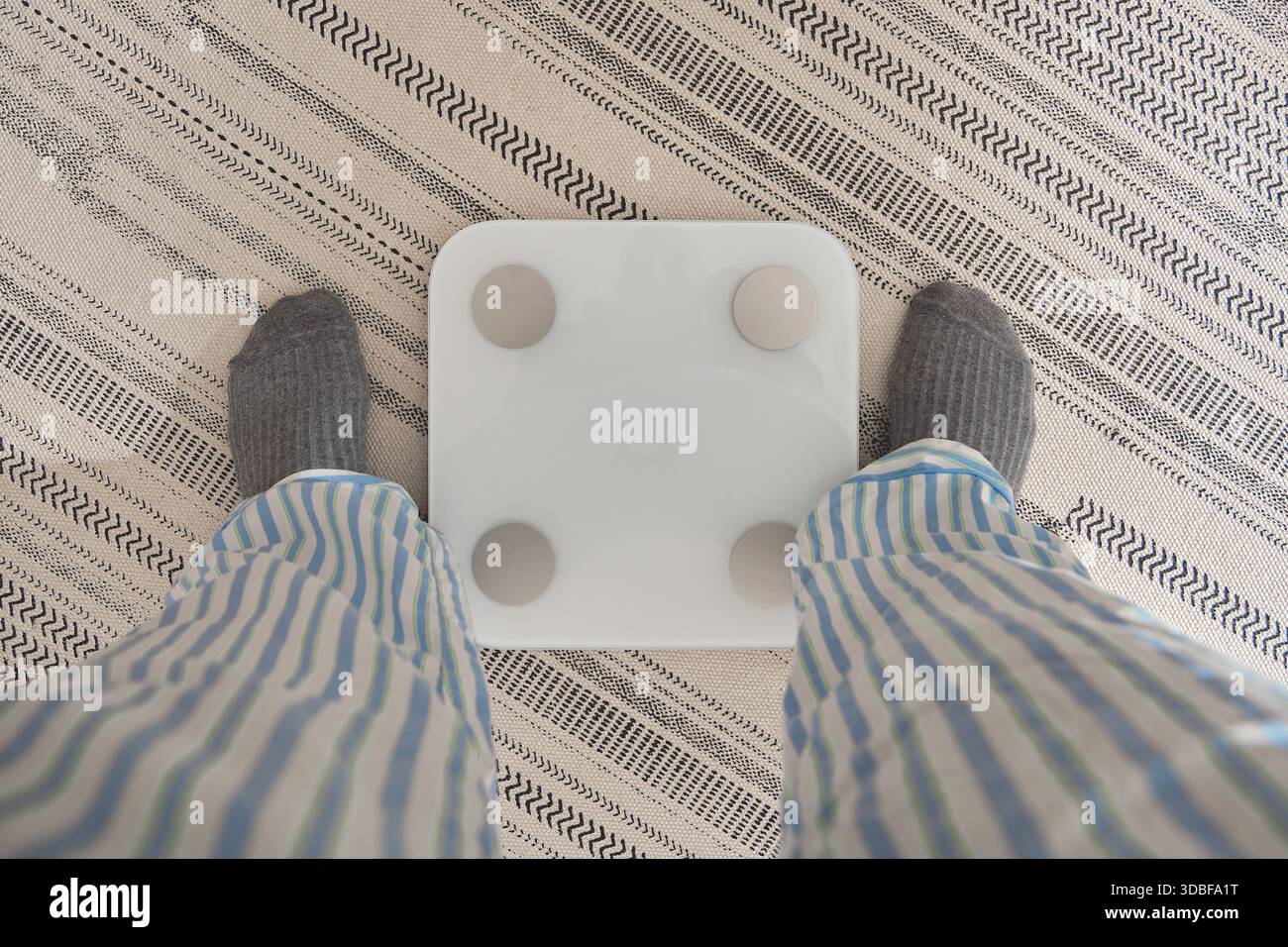 Persona che si pesa su una bilancia intelligente in pigiama, iniziando un viaggio di salute Foto Stock