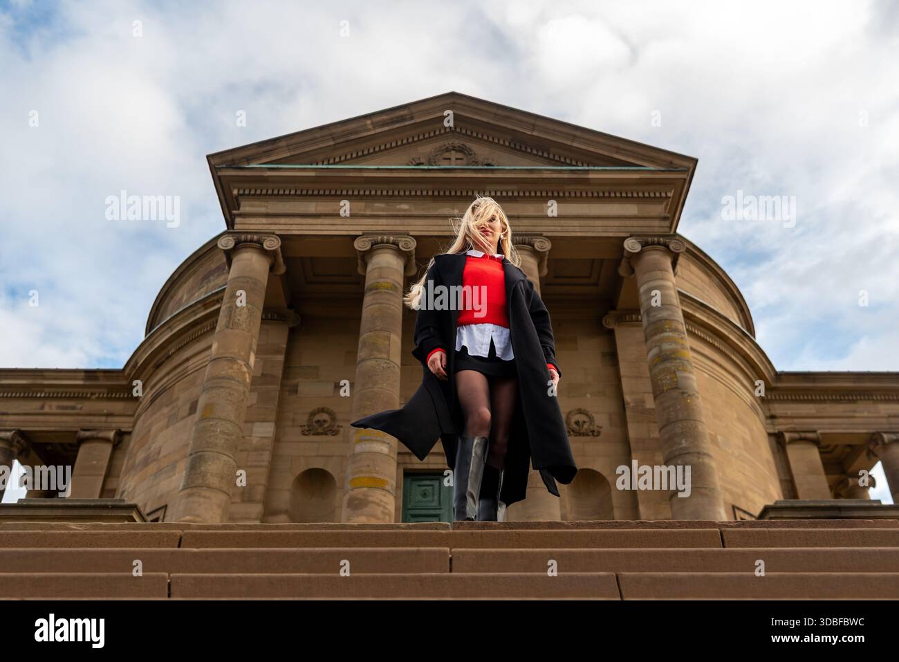 Donna elegante con capelli elastici in piedi di fronte a un edificio medievale Foto Stock