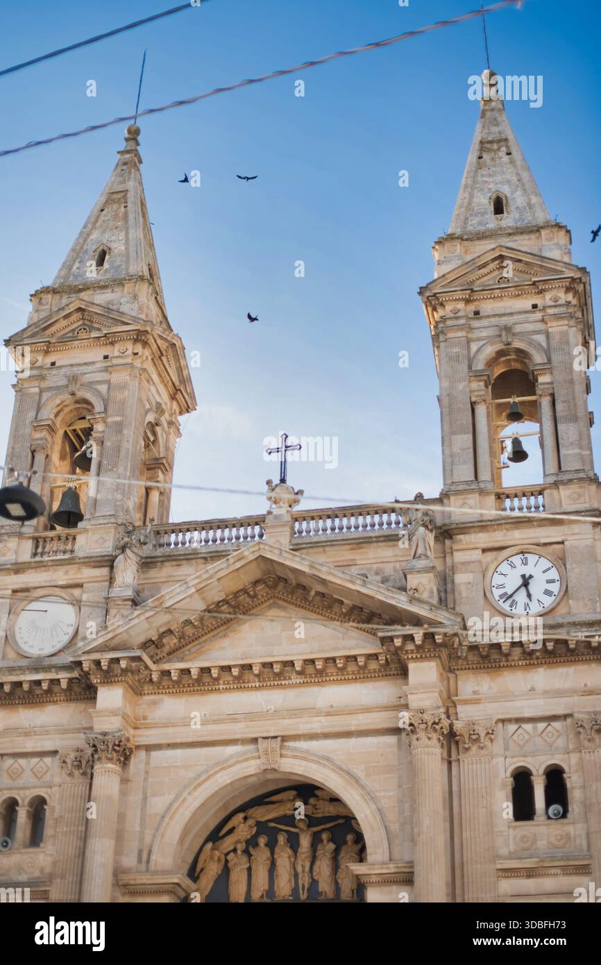 Facciata della storica chiesa barocca con le Torri Campanarie gemelle e l'orologio sotto il cielo azzurro nella città europea Foto Stock