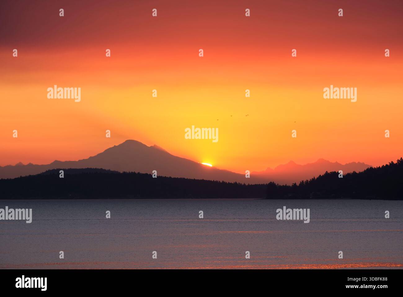Guardando dall'Isola di Vancouver in Canada sullo dritto della Georgia, proprio quando il sole sorge sul Monte Baker nello stato di Washington. Foto Stock