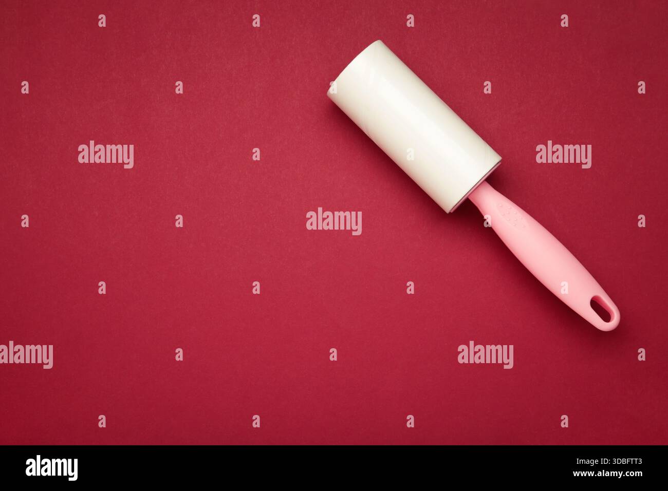 Spazzola a rullo per tessuti con carta su fondo rosso. Spazio per il testo Foto Stock