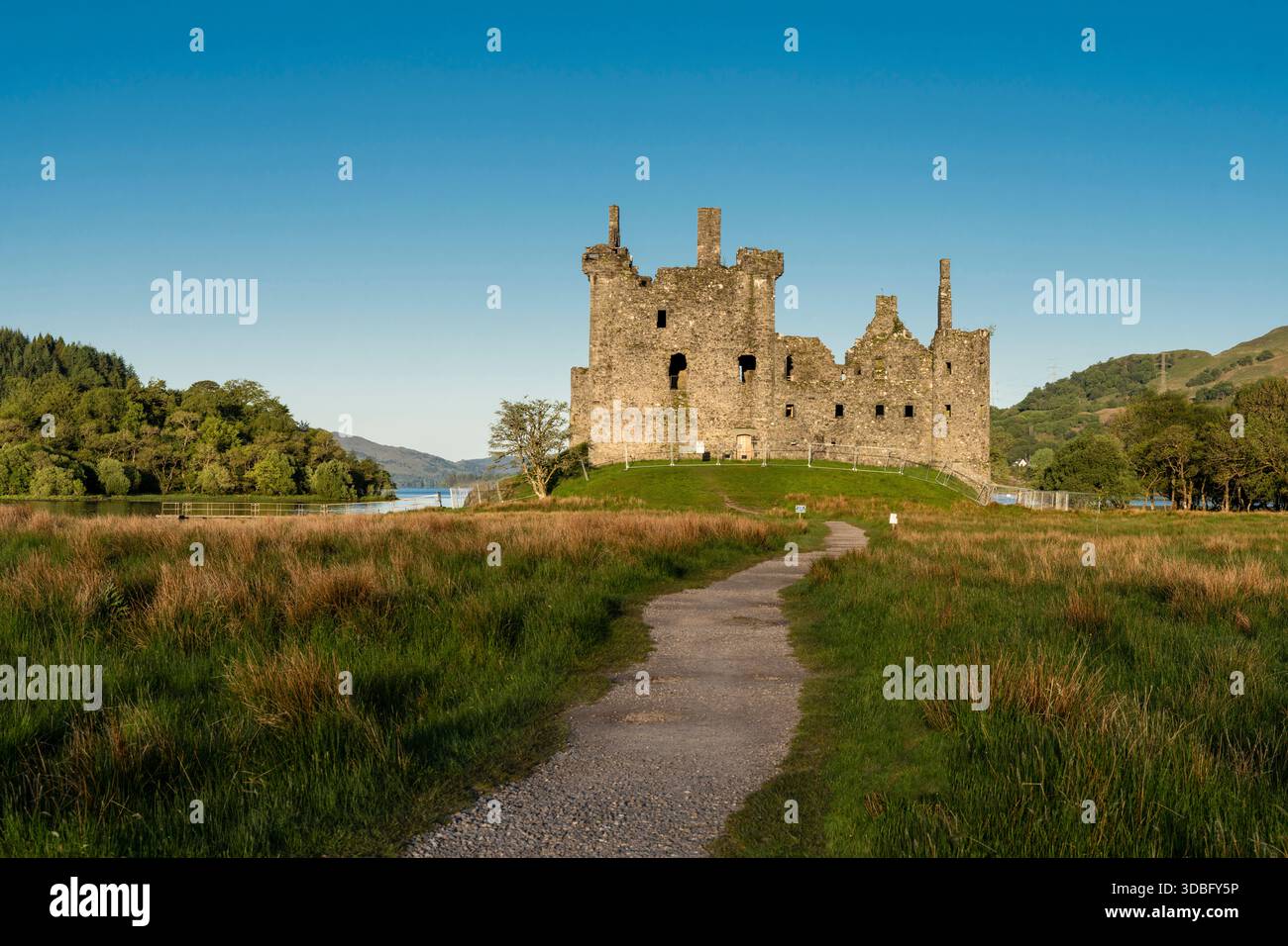Una vista spettacolare del castello di Kilchurn arroccato su una collina erbosa accanto a Loch Awe in Scozia. Le rovine di pietra intemperie si affacciano sulle acque tranquille e su rollin Foto Stock