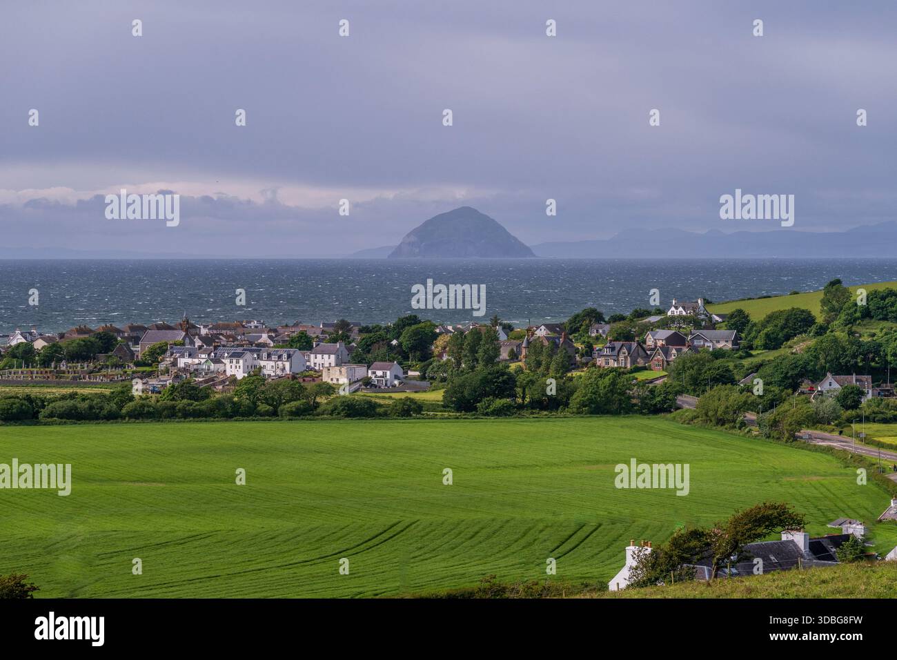 Paesino costiero panoramico di Ballantrae con campi verdi e Ailsa Craig all'orizzonte. Foto Stock