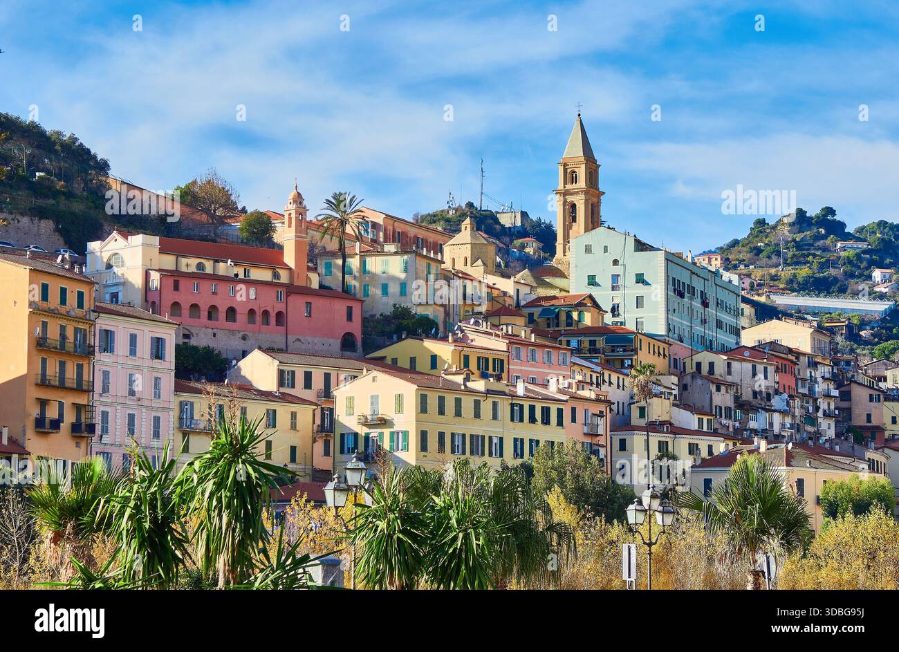 La soleggiata città costiera italiana di Ventimiglia, con edifici colorati, palme e una prominente Torre dell'Orologio Foto Stock