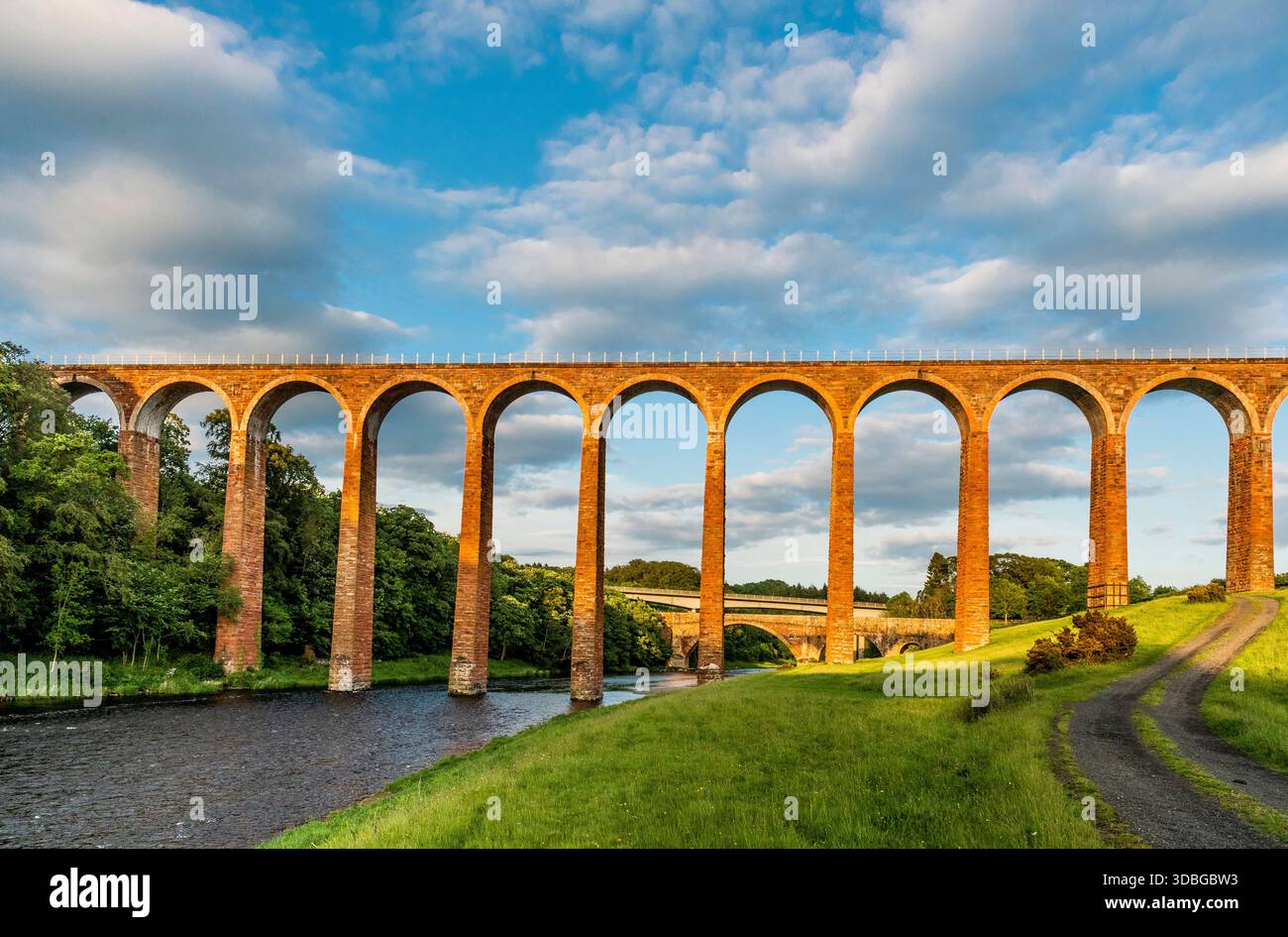 Lo storico viadotto Leaderfoot attraversa un fiume attraverso campi lussureggianti sotto un cielo blu. Foto Stock