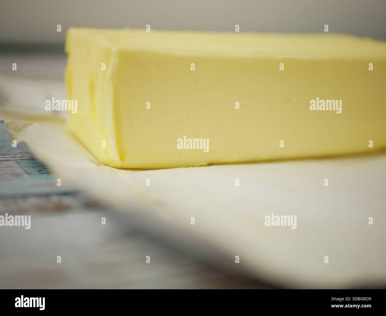Blocco di burro in pellicola d'argento aperta su superficie rustica in legno — primo piano ingrediente grasso lattico fresco per ricette di cottura e cottura Foto Stock