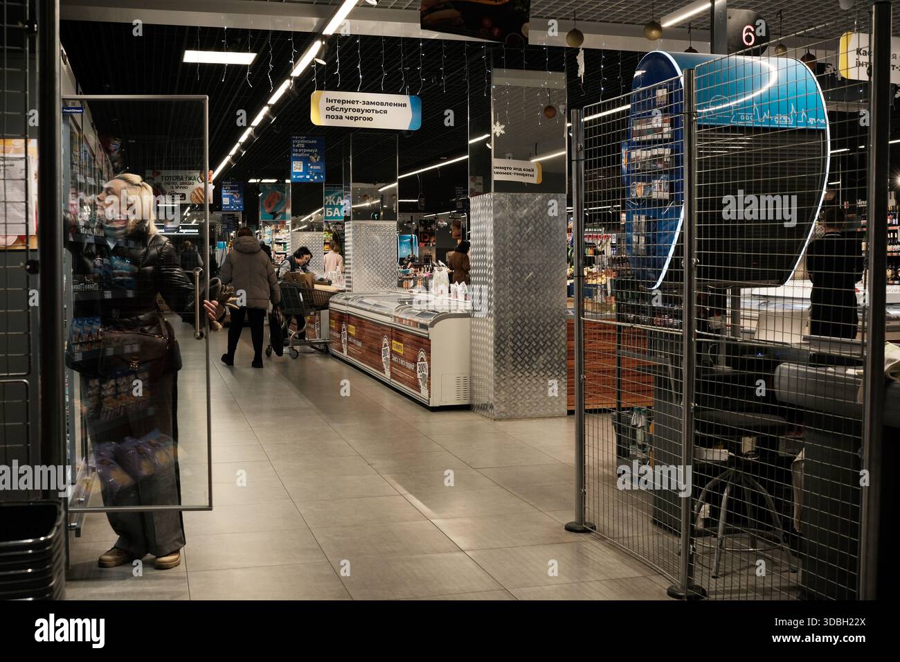 I clienti possono sfogliare diversi prodotti in un mercato vivace durante la sera. Metrograd. Kiev, Ucraina. 16 dicembre 2025. Foto Stock