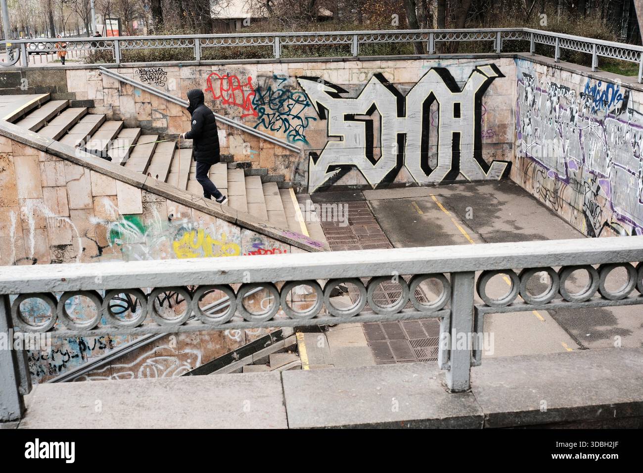Una figura solitaria scenderà le scale animate circondate da graffiti artistici. Shevchenko Boulevard. Kiev, Ucraina. 16 dicembre 2025. Foto Stock