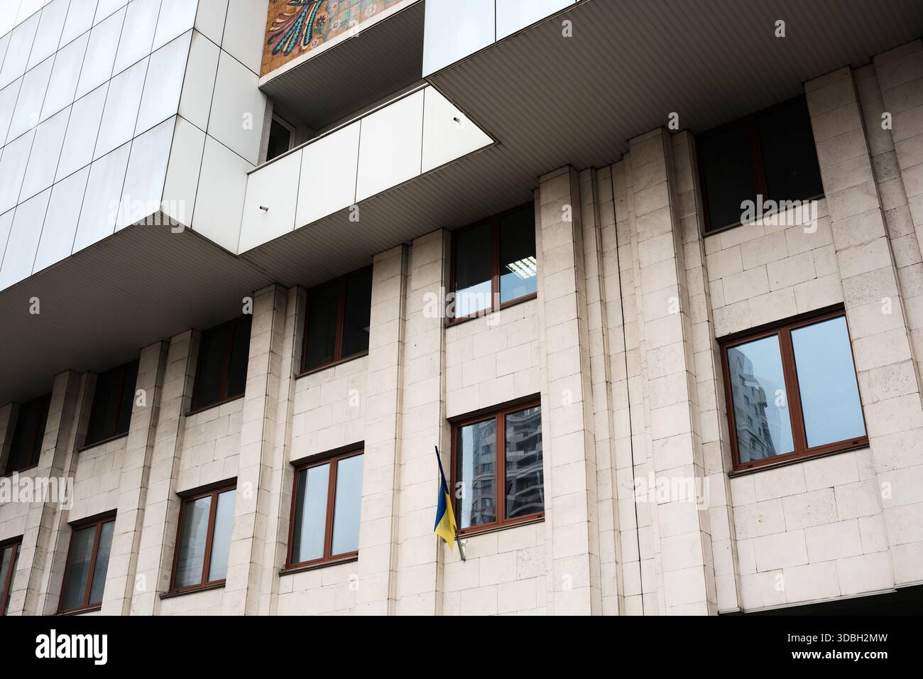 La bandiera Ucraina balla nella brezza su una moderna struttura governativa. Shevchenko Boulevard. Kiev, Ucraina. 16 dicembre 2025. Foto Stock