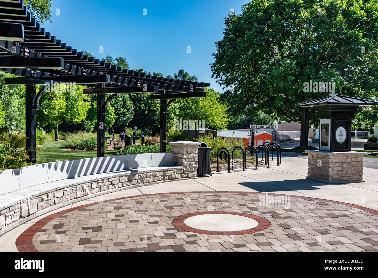 Centro di Algonquin Illinois plaza con pergolato moderno, pavimentazioni in mattoni, posti a sedere ricurvi in pietra e verde paesaggistico che creano un'accogliente area comunitaria. Foto Stock