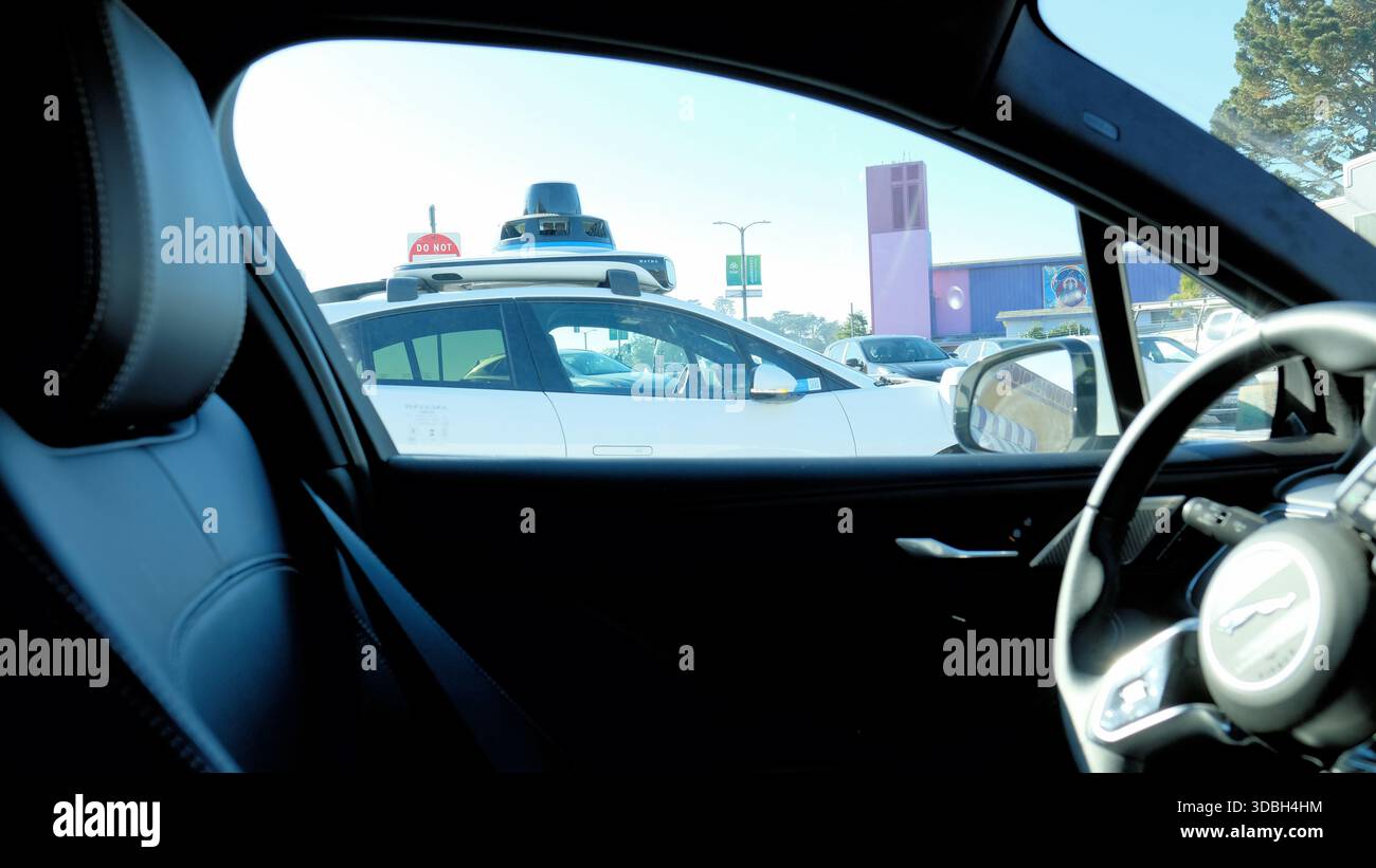 Robot taxi senza conducente autonomo Waymo vuoto visto da un altro Waymo attraverso il finestrino lato conducente; Waymos uno accanto all'altro; San Francisco, California. Foto Stock