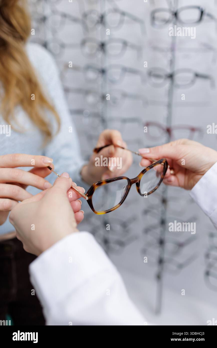 Primo piano dell'ottica che aiuta il cliente a montare le cornici degli occhiali nello showroom concetto di servizio di cura della vista e acquisto di occhiali Foto Stock
