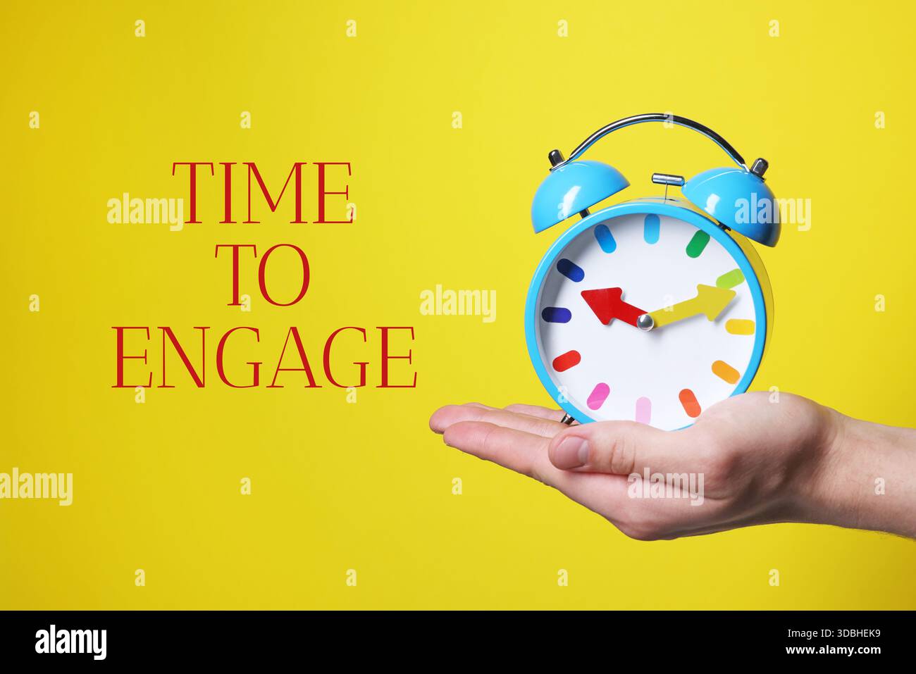 È ora di impegnarsi. Uomo che tiene la sveglia su sfondo giallo, primo piano Foto Stock
