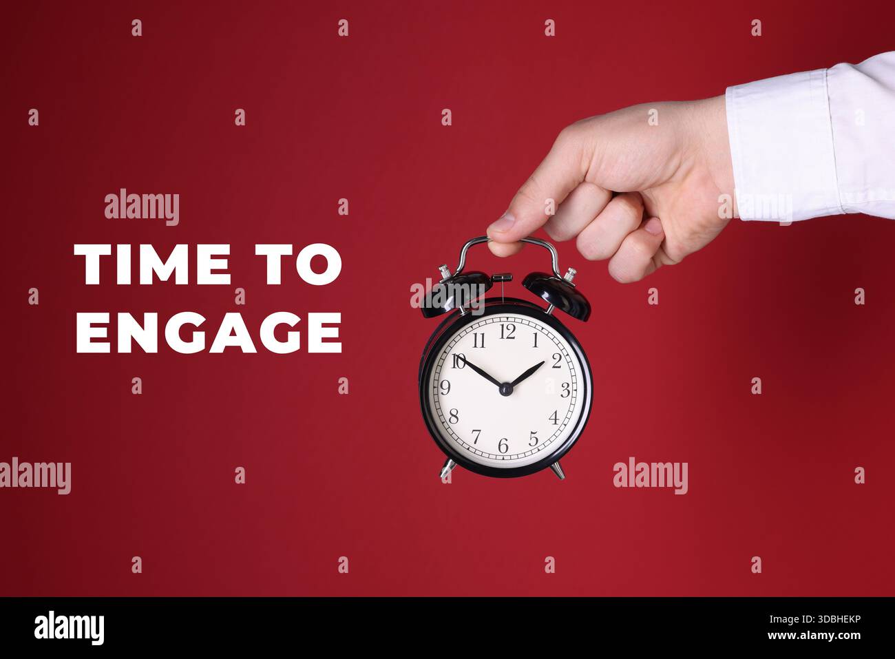 È ora di impegnarsi. Uomo che tiene la sveglia su sfondo rosso, primo piano Foto Stock
