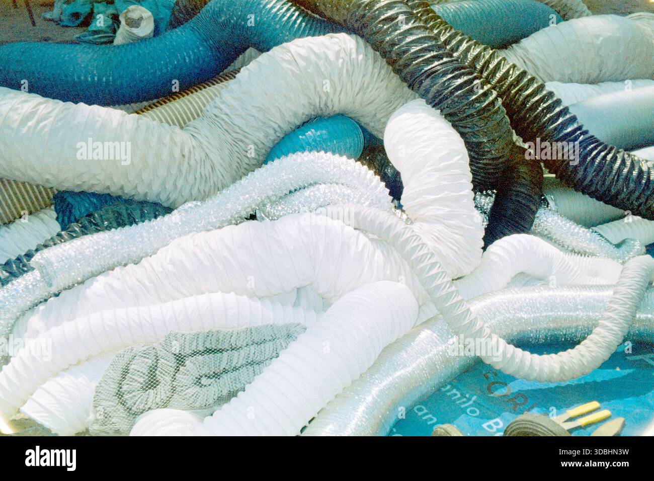 Nuovi tubi di ventilazione ondulati in plastica impilati sul mercato, composizione astratta, catturati su pellicola analogica da 35 mm. Foto Stock
