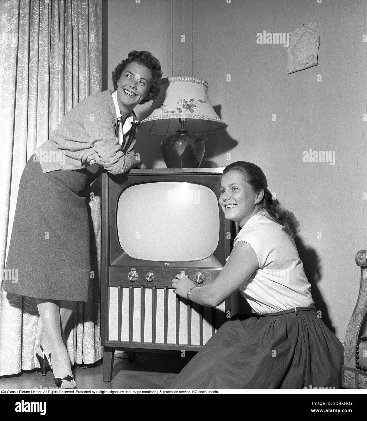 Un televisore del 1950s.questo è uno dei primi televisori con il tipico design degli anni '1950, in grado di visualizzare solo trasmissioni in bianco e nero da un singolo canale (comune in Svezia all'epoca). Le manopole sulla parte anteriore controllano l'immagine e l'audio. La foto mostra la popolare attrice svedese Sickan Carlsson (1915-2011) con sua figlia Ingegerd Reuter nel 1958. Sickan Carlsson è stata una delle star del cinema più amate della Svezia dagli anni '1930 agli anni '1950, nota per i suoi ruoli allegri in commedie leggere e musical. Spesso chiamata "la fidanzata della Svezia", è stata l'attrice più pagata del paese durante lei Foto Stock