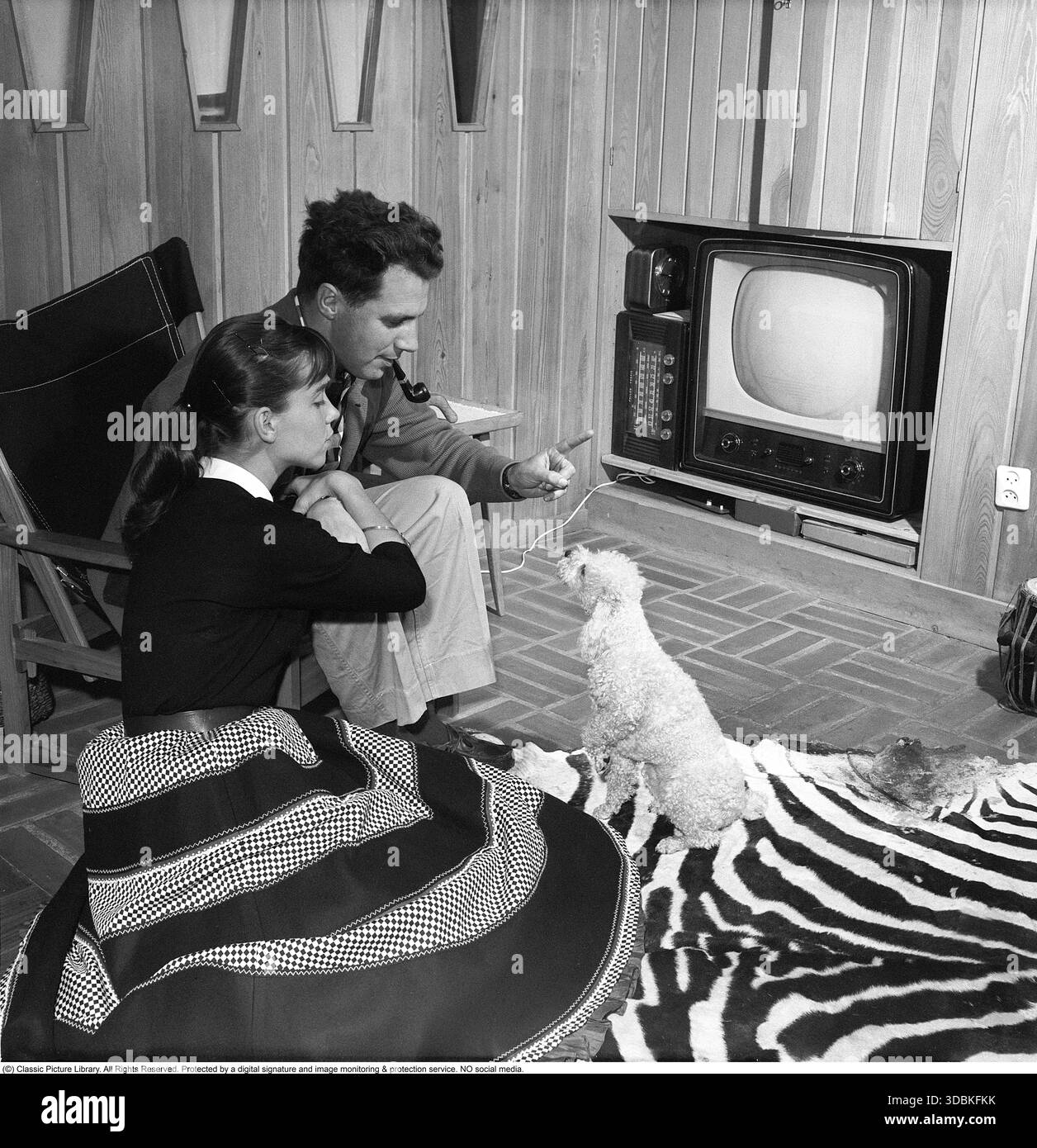 Televisione negli anni '1950 Uno dei primi televisori con solo la possibilità di visualizzare trasmissioni televisive in bianco e nero. Le manopole sulla parte anteriore controllano l'immagine e l'audio. Gunwer Bergkvist, attrice svedese nata il 3 agosto 1932. Qui a casa con suo marito, il regista Hans Lagerkvist, nel 1957. Il televisore è un apparecchio Philips, con la scheda di prova chiaramente visibile sullo schermo. Sul pavimento si trova una pelle zebra. Foto Stock