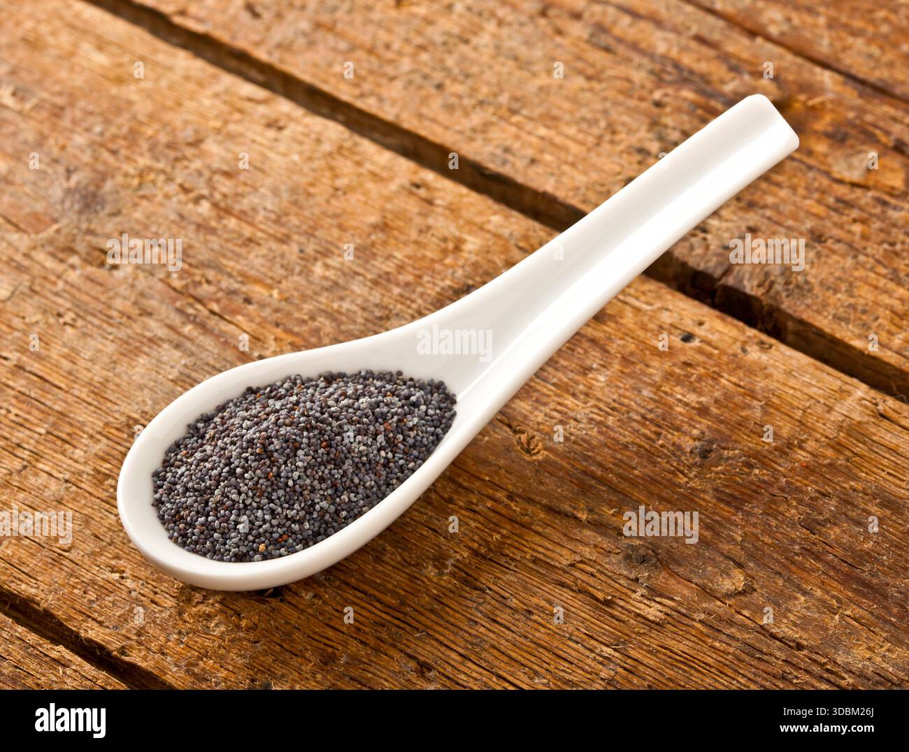 Semi di papavero in il cucchiaio sul tavolo di legno Foto Stock