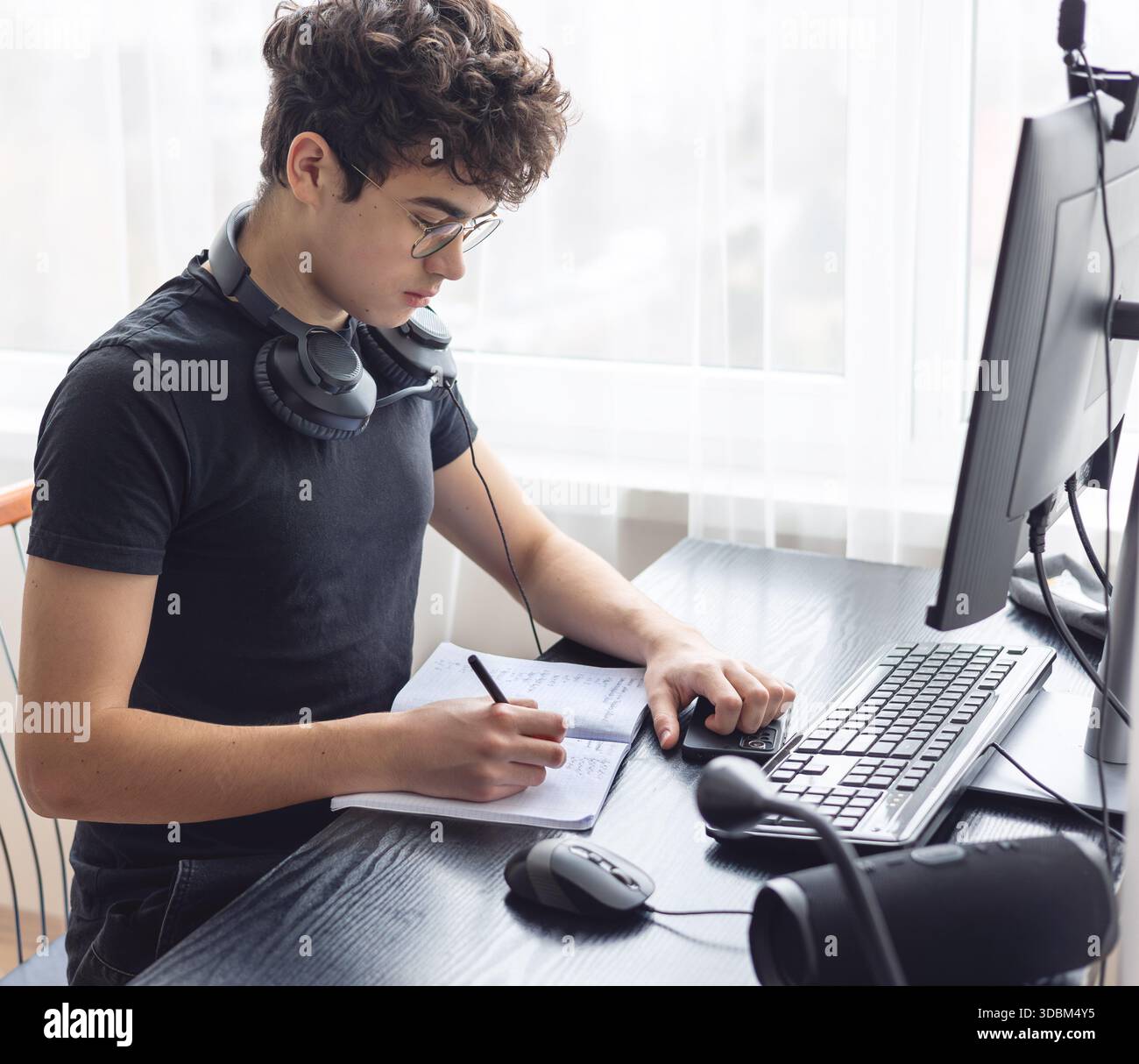 Adolescente che studia a casa con un computer. Teen freelance che lavora a un progetto a casa. Preparazione all'esame. Teen Boy che studia online. Foto Stock