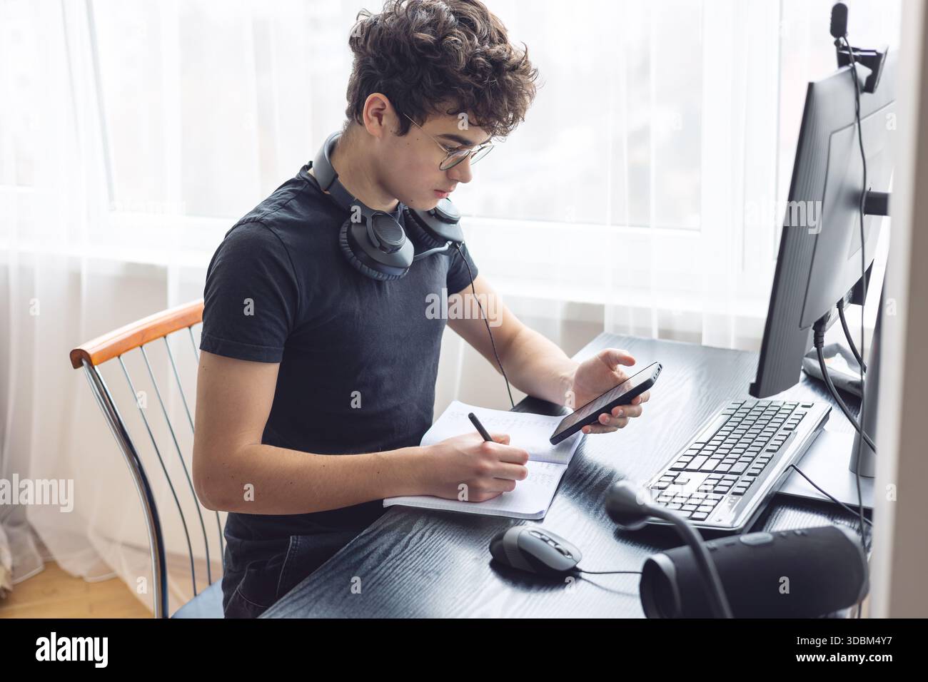 Adolescente che studia a casa con un computer. Teen freelance che lavora a un progetto a casa. Preparazione all'esame. Teen Boy che studia online. Foto Stock