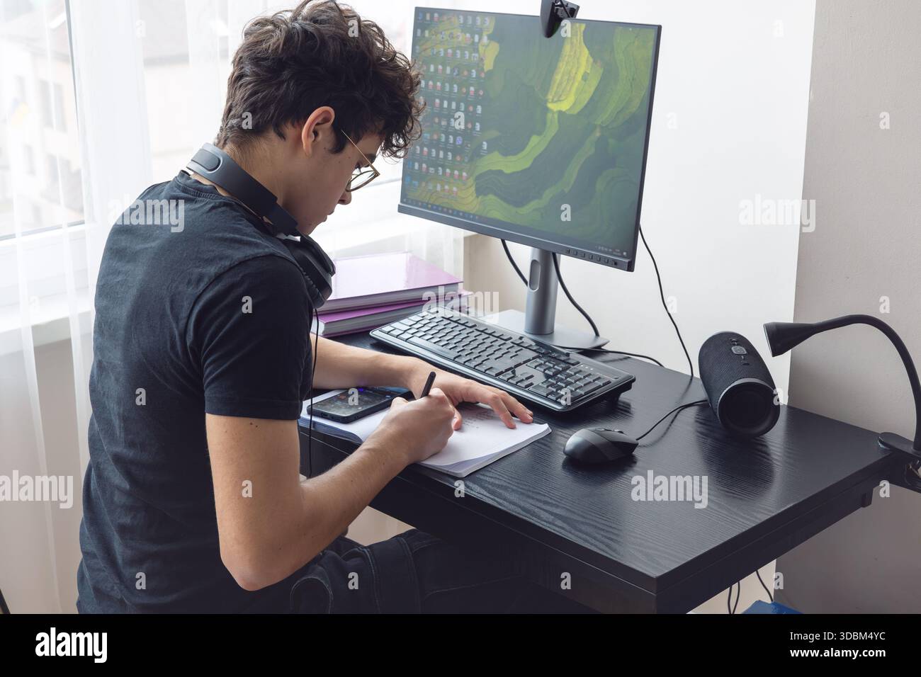 Adolescente che studia a casa con un computer. Teen freelance che lavora a un progetto a casa. Preparazione all'esame. Teen Boy che studia online. Foto Stock
