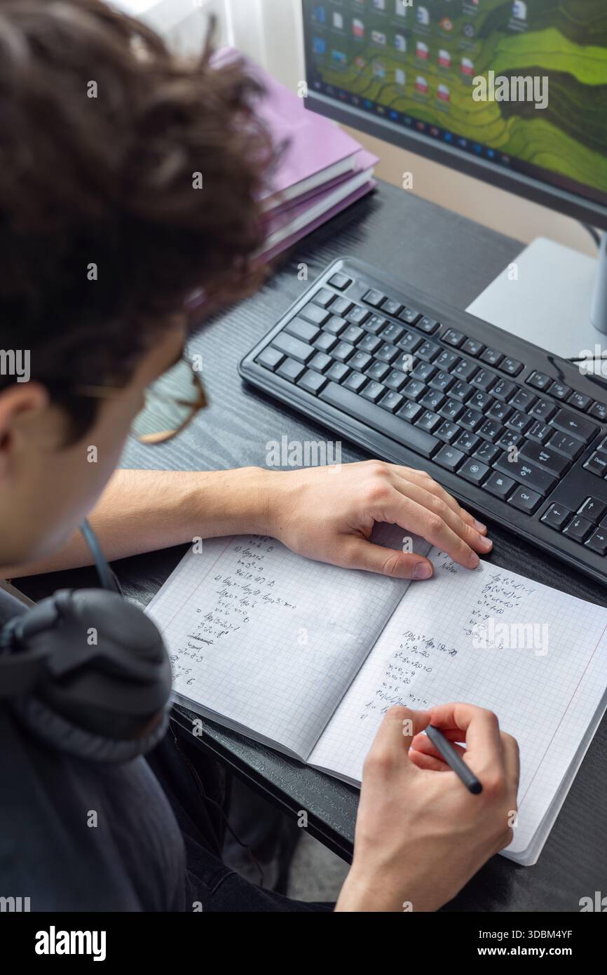 Adolescente che studia a casa con un computer. Teen freelance che lavora a un progetto a casa. Preparazione all'esame. Teen Boy che studia online Foto Stock