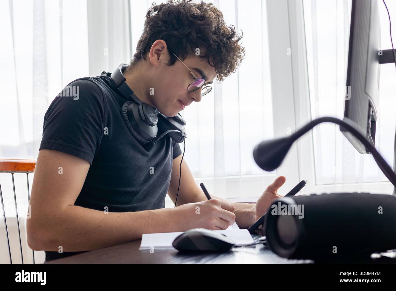 Adolescente che studia a casa con un computer. Teen freelance che lavora a un progetto a casa. Preparazione all'esame. Teen Boy che studia online. Foto Stock
