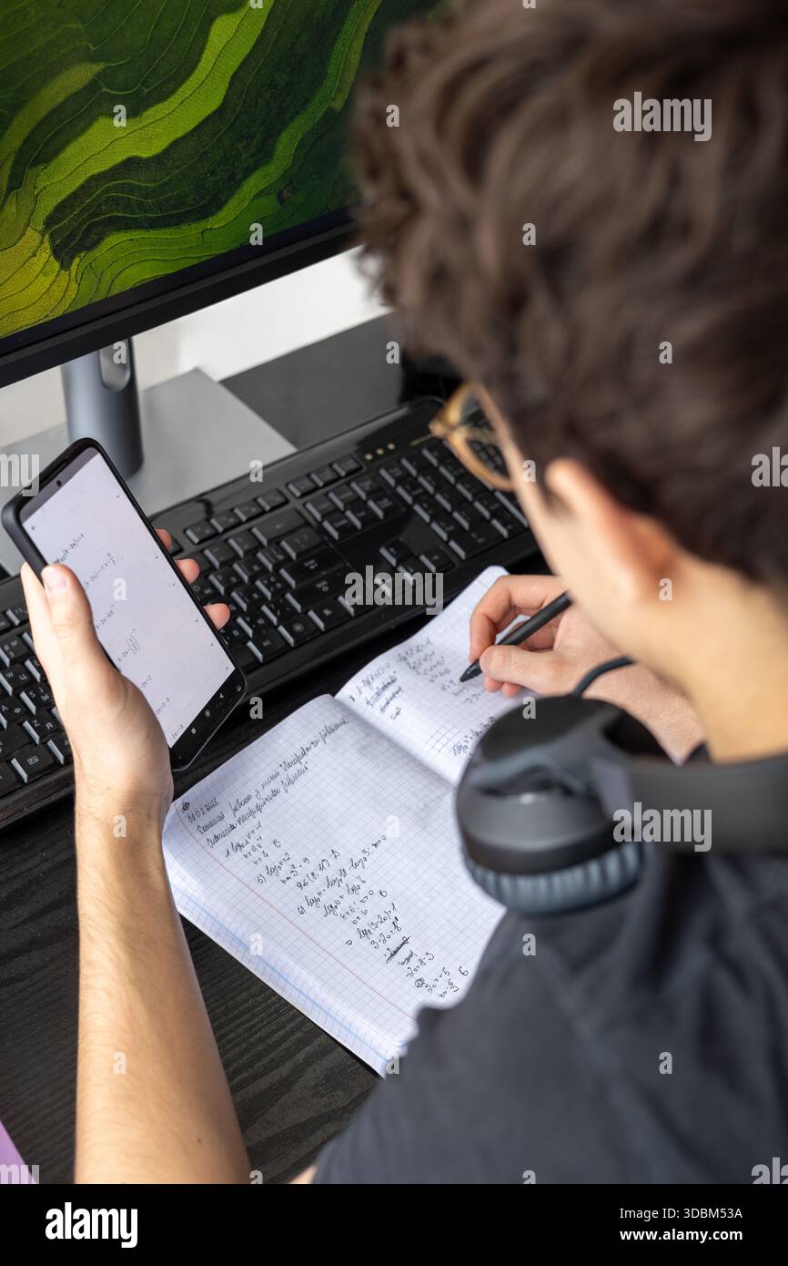 Adolescente che studia a casa con un computer. Teen freelance che lavora a un progetto a casa. Preparazione all'esame. Teen Boy che studia online Foto Stock
