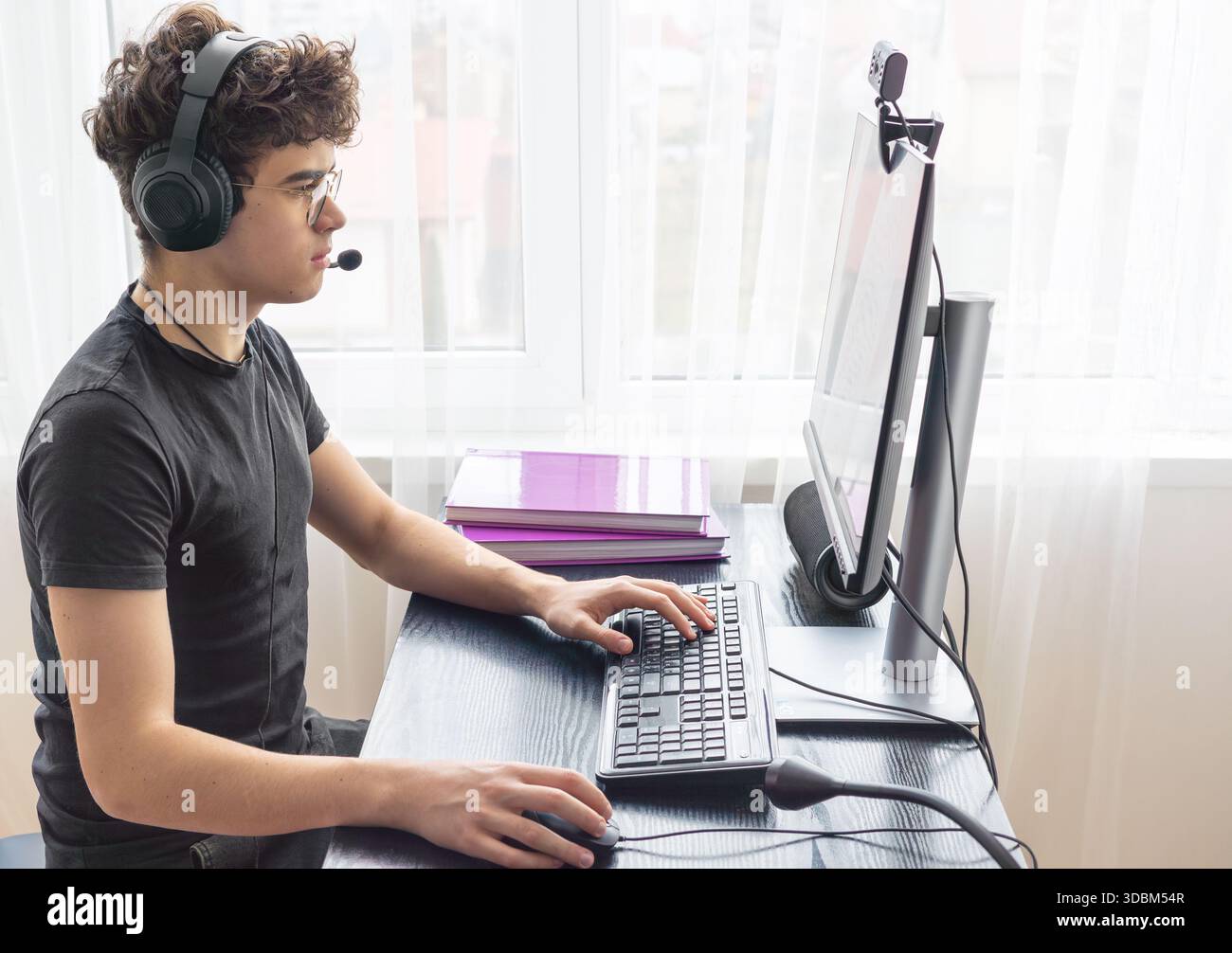 Teenager giocatore di eSport che si concentra su un gioco. Adolescenti che utilizzano la tecnologia per l'apprendimento e il gaming. Videogamer adolescente che gioca su un computer. Imparare online a casa. prigioniero Foto Stock