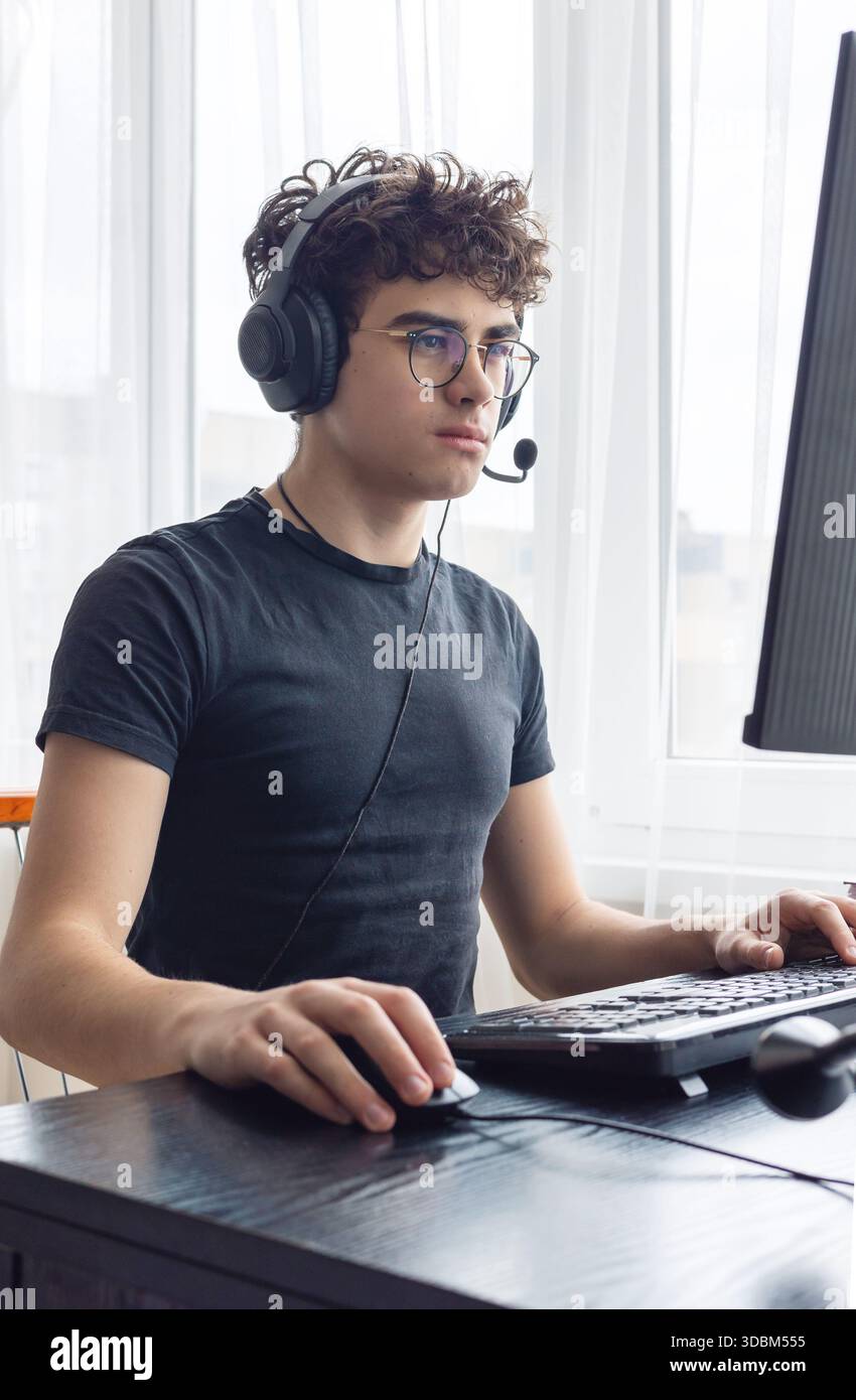 Teenager giocatore di eSport che si concentra su un gioco. Adolescenti che utilizzano la tecnologia per l'apprendimento e il gaming. Videogamer adolescente che gioca su un computer. Imparare online a casa. prigioniero Foto Stock