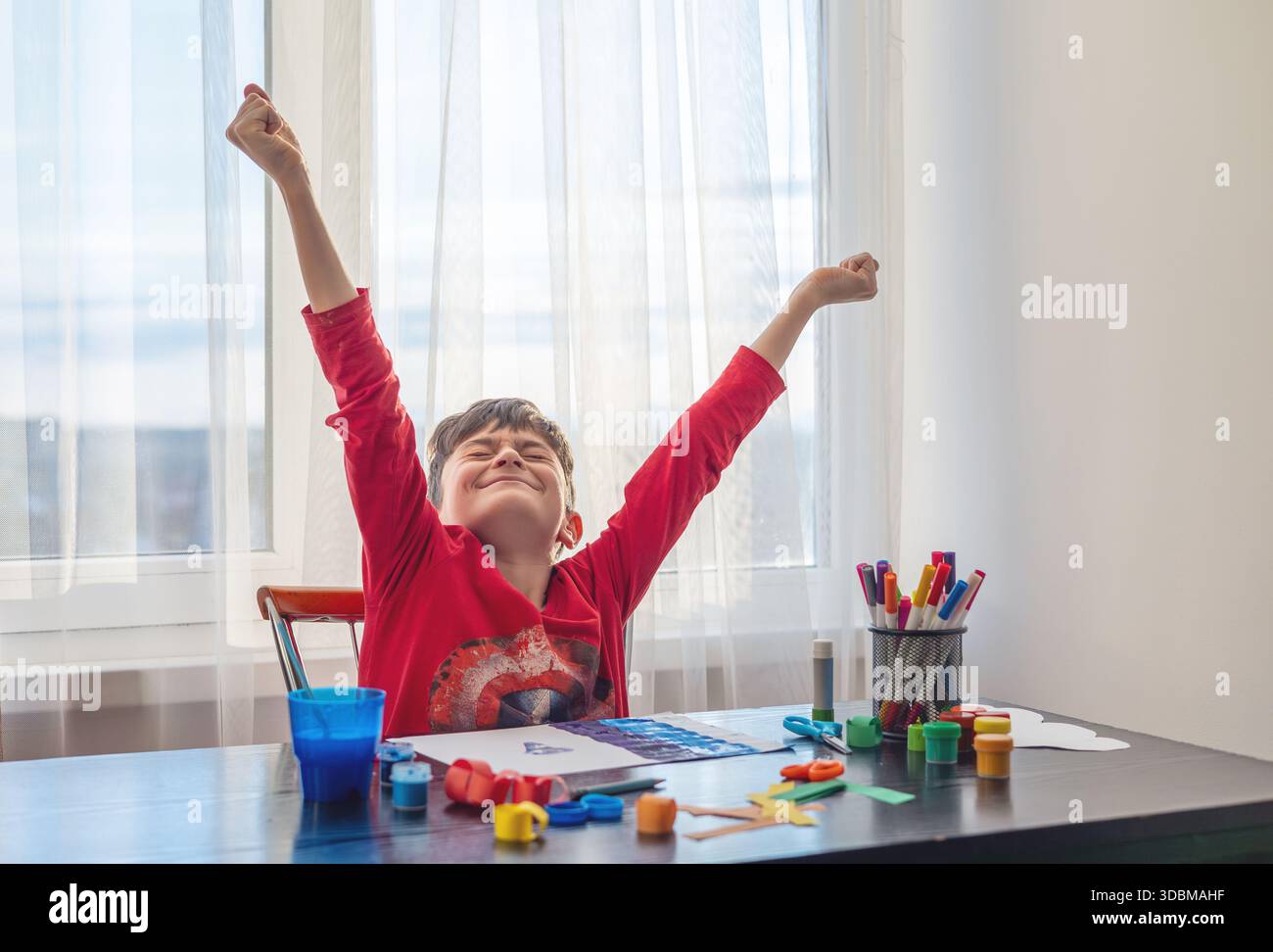Un ragazzo disegna a un tavolo pieno di materiali d'arte colorati, temi di creatività, autoespressione ed equilibrio emotivo, arte terapia. bambini con auti Foto Stock