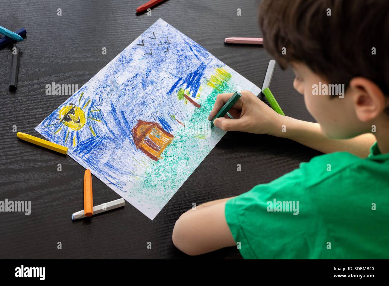 Focused Child in Green T-shirt Drawing with Crayons - Art Therapy for Autism, ADHD e Digital Detox Concept. ragazzo che disegna con colori pastello. Foto Stock