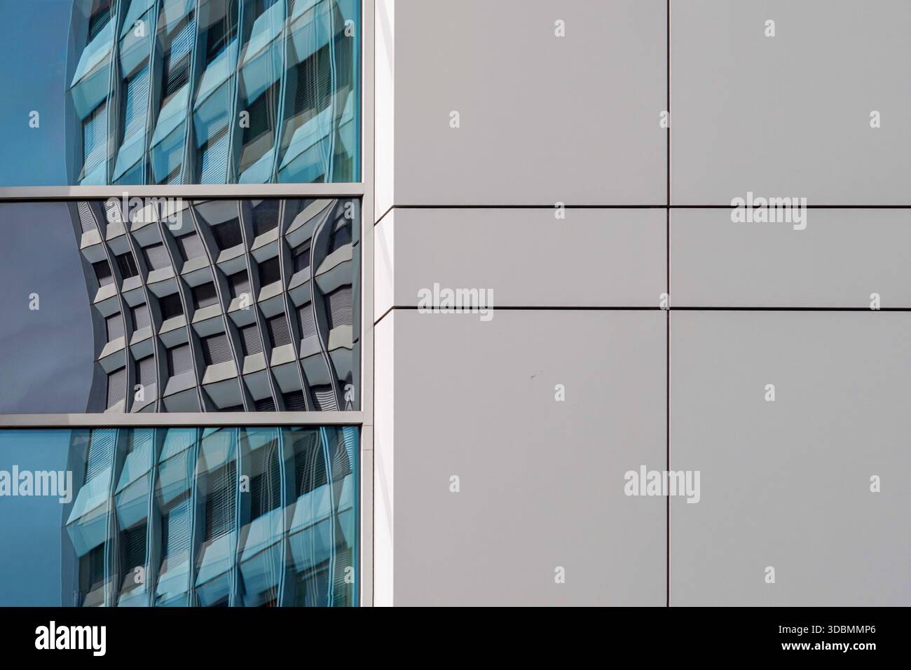 Riflessioni del progresso: Reti invisibili. Una facciata di uffici a Ginevra, Svizzera, rispecchia il grattacielo dell'Unione Internazionale delle telecomunicazioni. Progettata da Andre Bordigoni nel 1970, la torre di 57 metri simboleggia la connettività globale. Foto Stock