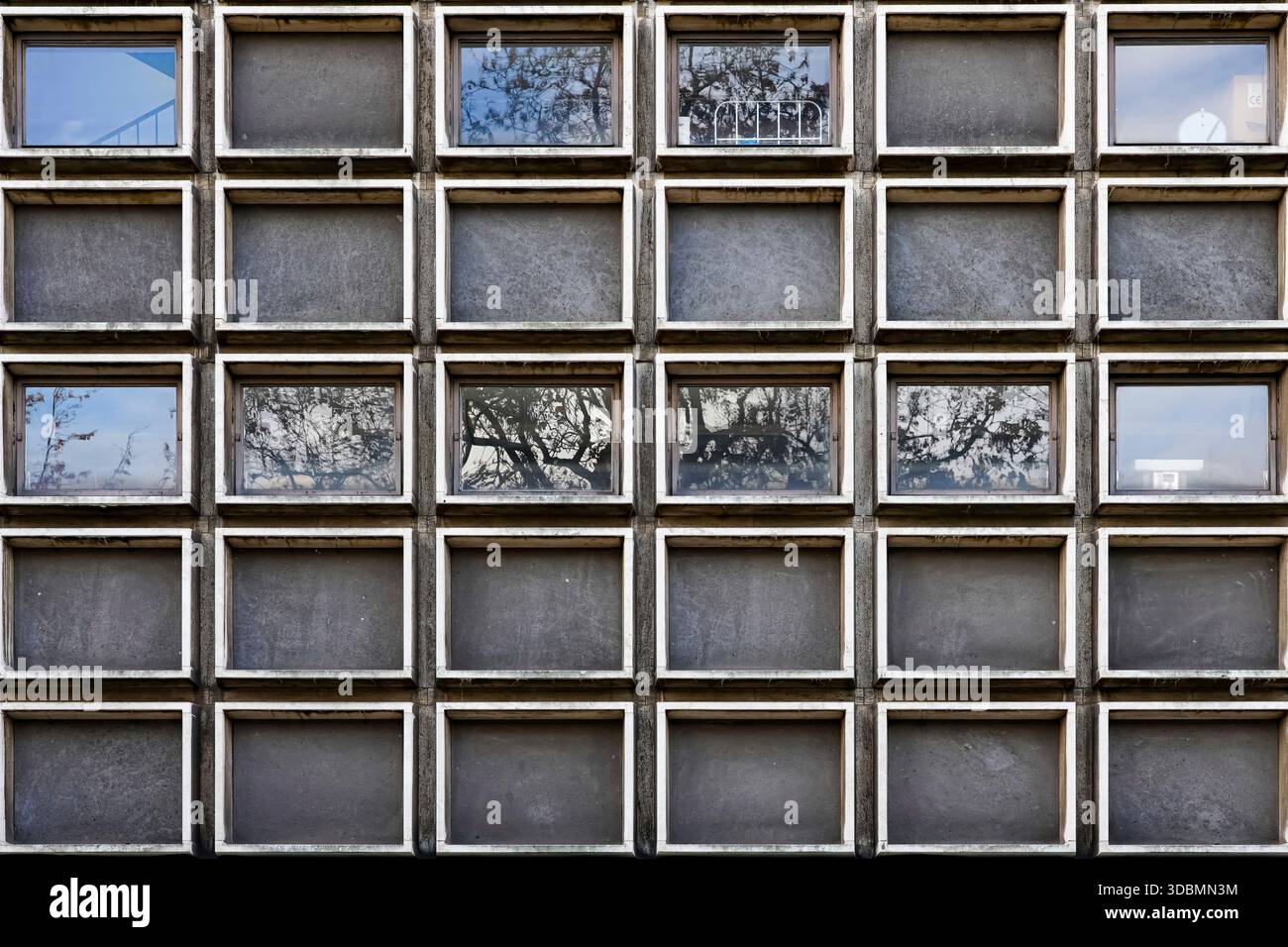 Facciata dell'edificio commerciale, Hannover, Germania, griglia di finestre quadrate con pannelli chiari e opachi che riflettono il cielo e gli alberi. Foto Stock