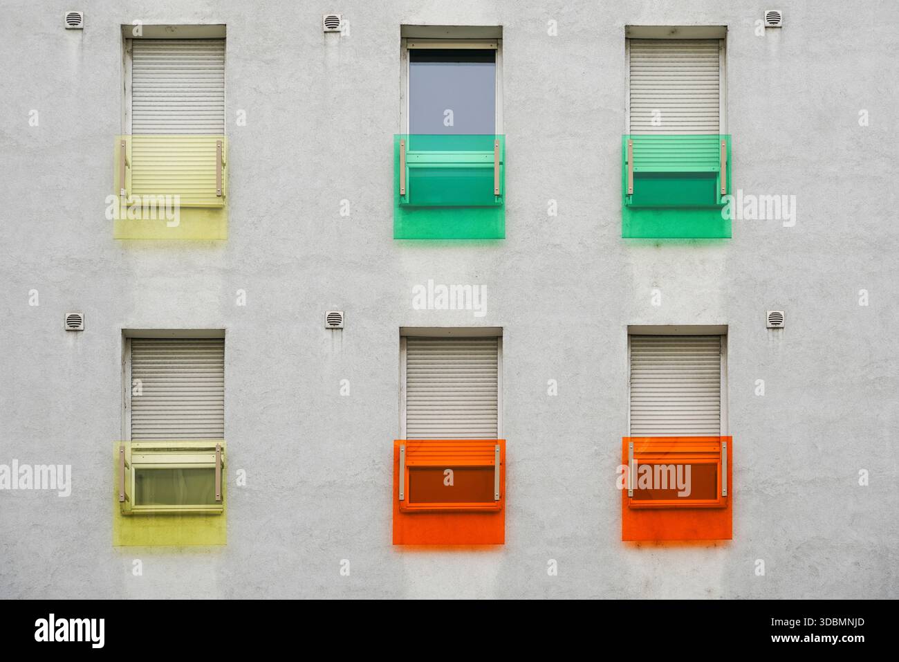 Finestre colorate, Grenoble, Francia, facciata residenziale, persiane colorate, finestra gialla, finestra verde, finestra arancione, parete grigia, design urbano, estetica giocosa, ritmo geometrico Foto Stock