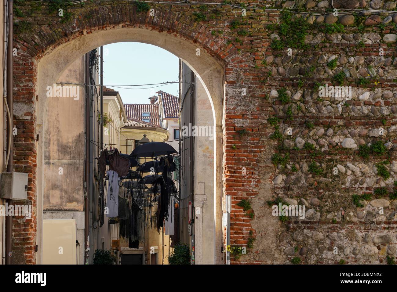 Bassano del Grappa, Italia, vista sulla strada con decorazioni di Halloween appese tra gli edifici, tra cui figure scure e ombrelli neri sospesi sopra lo stretto vicolo Foto Stock