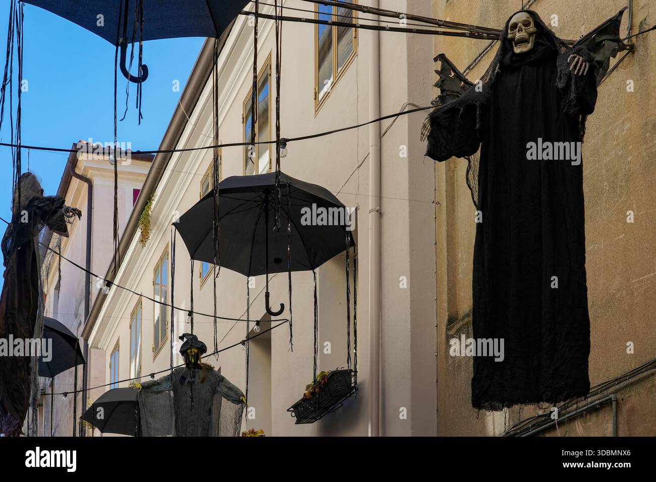 Bassano del Grappa, Italia, vista sulla strada con decorazioni di Halloween appese tra gli edifici, tra cui figure scure e ombrelli neri sospesi sopra lo stretto vicolo Foto Stock