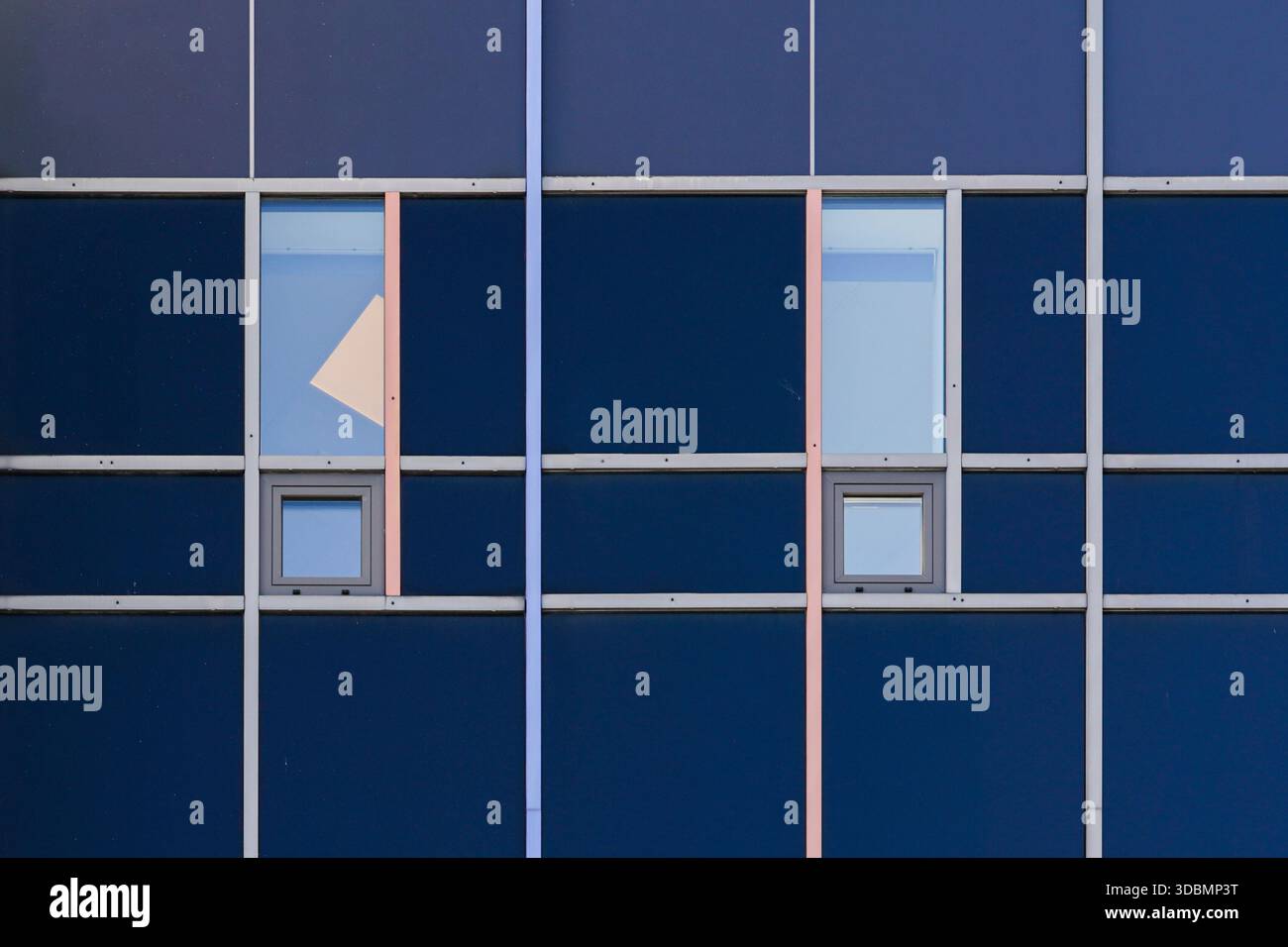 Stoccolma, Svezia, facciata minimalista dell'edificio con una griglia di pannelli blu scuro, sottili cornici metalliche, piccole finestre quadrate, due grandi finestre rettangolari e una forma triangolare tagliata su un unico pannello Foto Stock