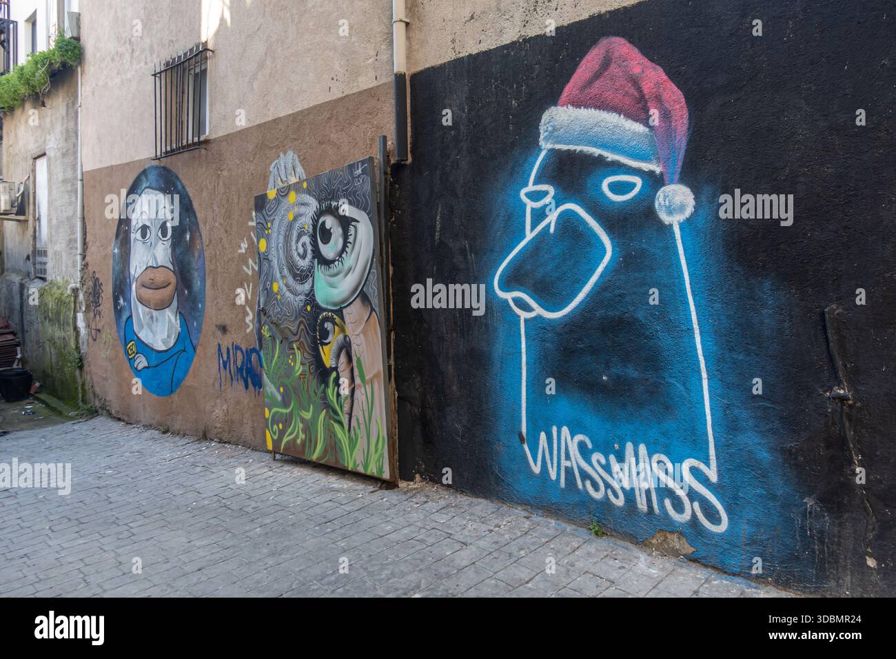 street art in un vicolo, caratterizzato da un'importante opera di graffiti blu e bianchi su una parete nera, figura stilizzata del cappello di Babbo Natale, Istanbul turchia, beyouglu Foto Stock