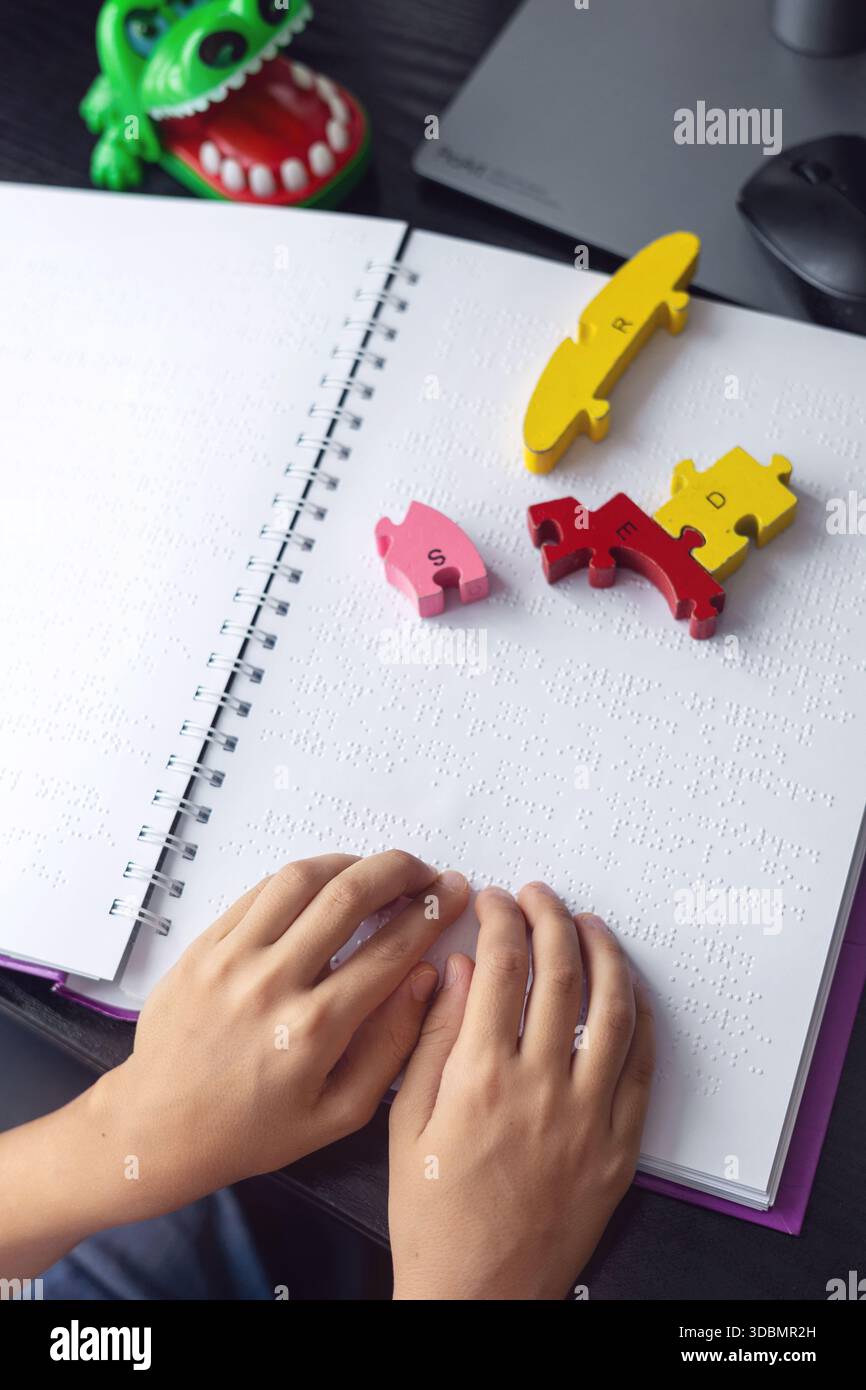 Le mani dei bambini su un libro in Braille – inclusione, cecità, disabilità Foto Stock