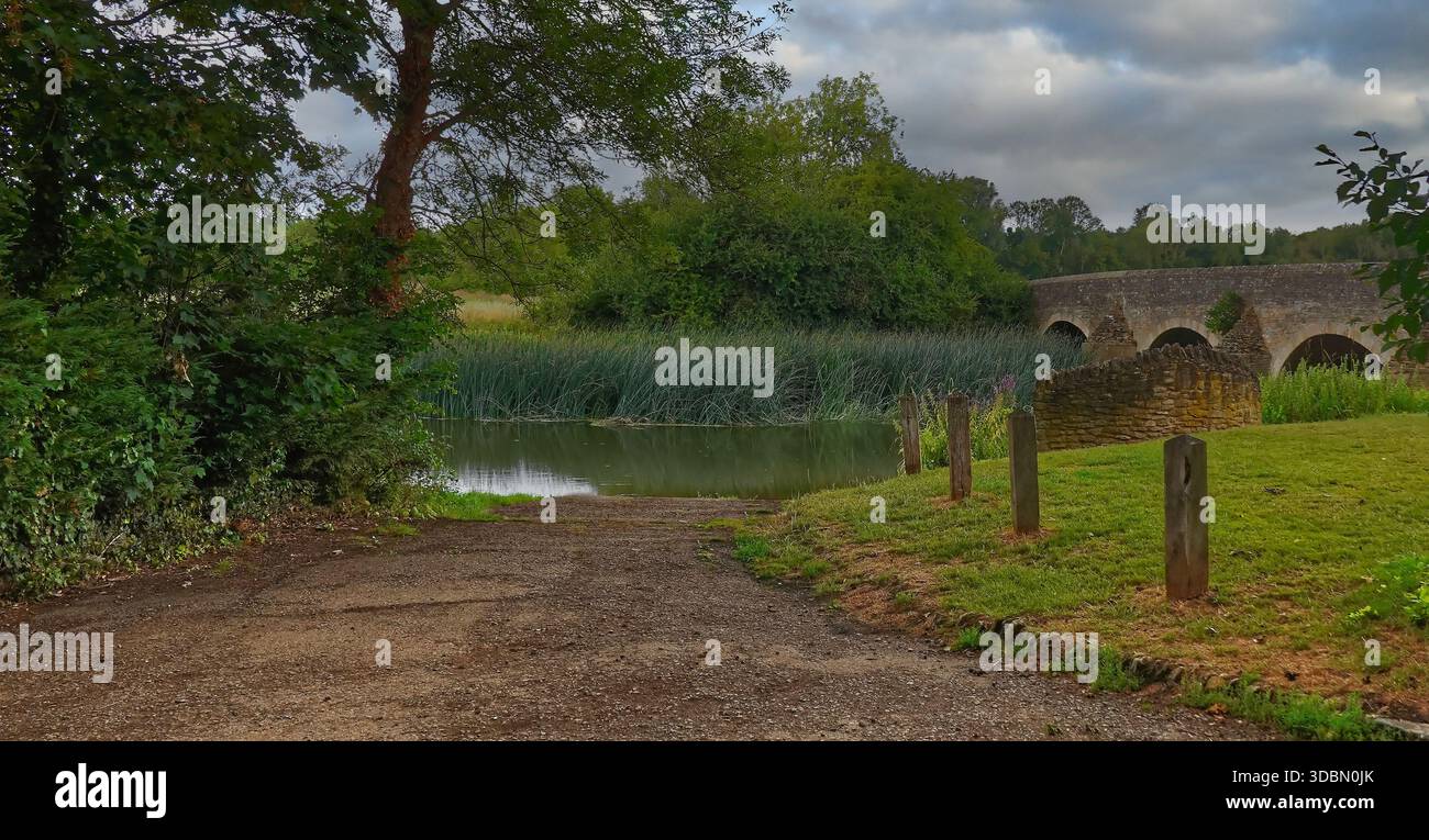 Percorso che conduce al fiume Great Ouse al ponte Felmersham, Bedfordshire, Regno Unito, con riflessi nell'acqua Foto Stock