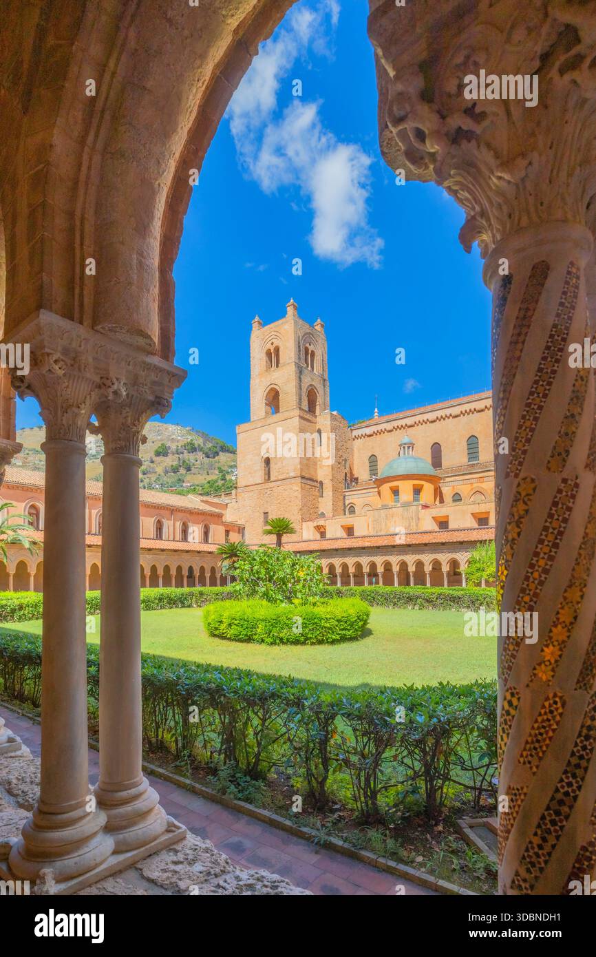 Vista del chiostro benedettino di Monreale, con archi in pietra ornamentali, capitelli scolpiti, colonne, palme e il campanile medievale della Cattedrale di Monreale, un capolavoro dell'architettura normanna. Città metropolitana di Palermo, Sicilia, Italia Foto Stock