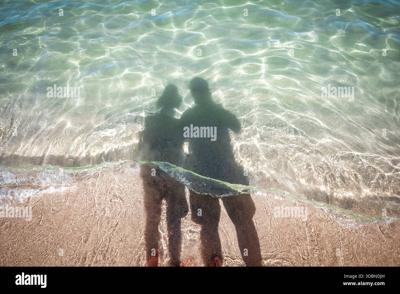 Ombre di una coppia riflesse sul litorale con acque cristalline a Mondello Beach, una famosa destinazione balneare di Palermo. Palermo, Provincia di Palermo, Sicilia, Italia Foto Stock