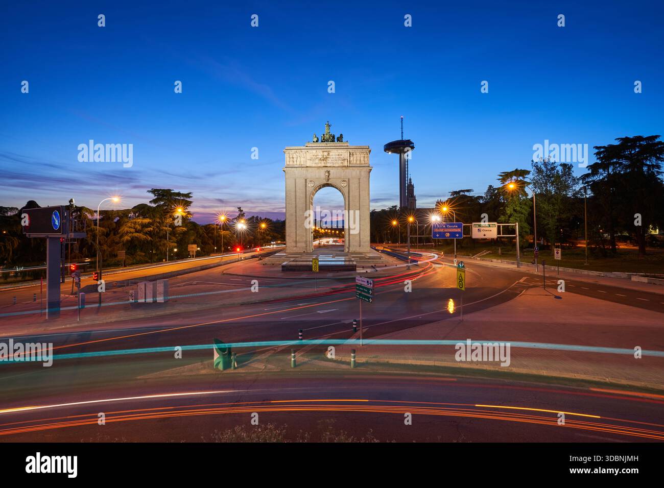 L'Arco della Vittoria di Moncloa illuminato all'ora blu a Madrid, con sentieri leggeri provenienti dalle auto di passaggio Foto Stock