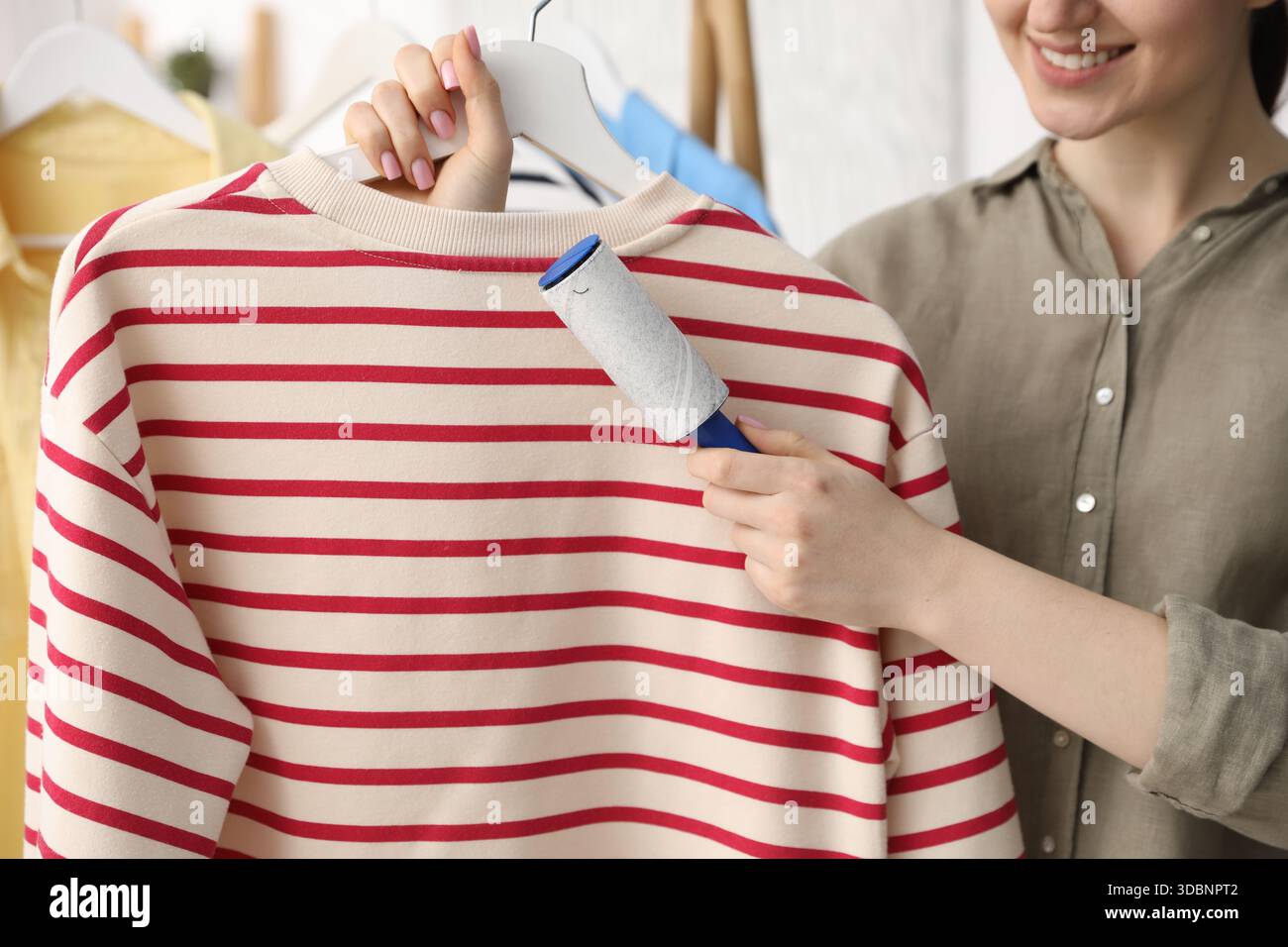 Donna che pulisce la felpa con rullo di lanugine a casa, primo piano Foto Stock