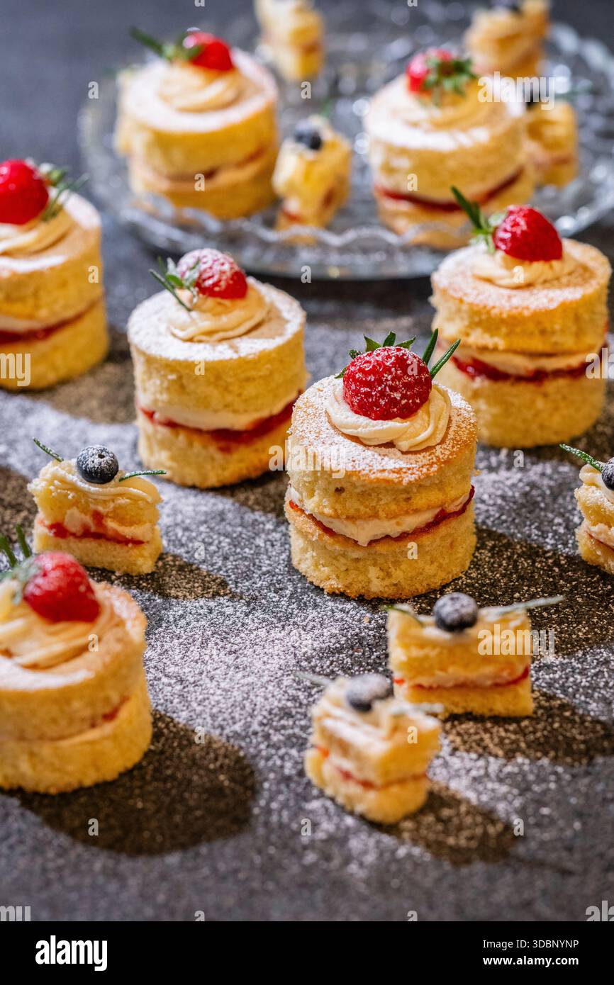 Tortine di spugne Victoria su misura, torte individuali piccole decorate su un piano di lavoro, West Sussex, Inghilterra Foto Stock