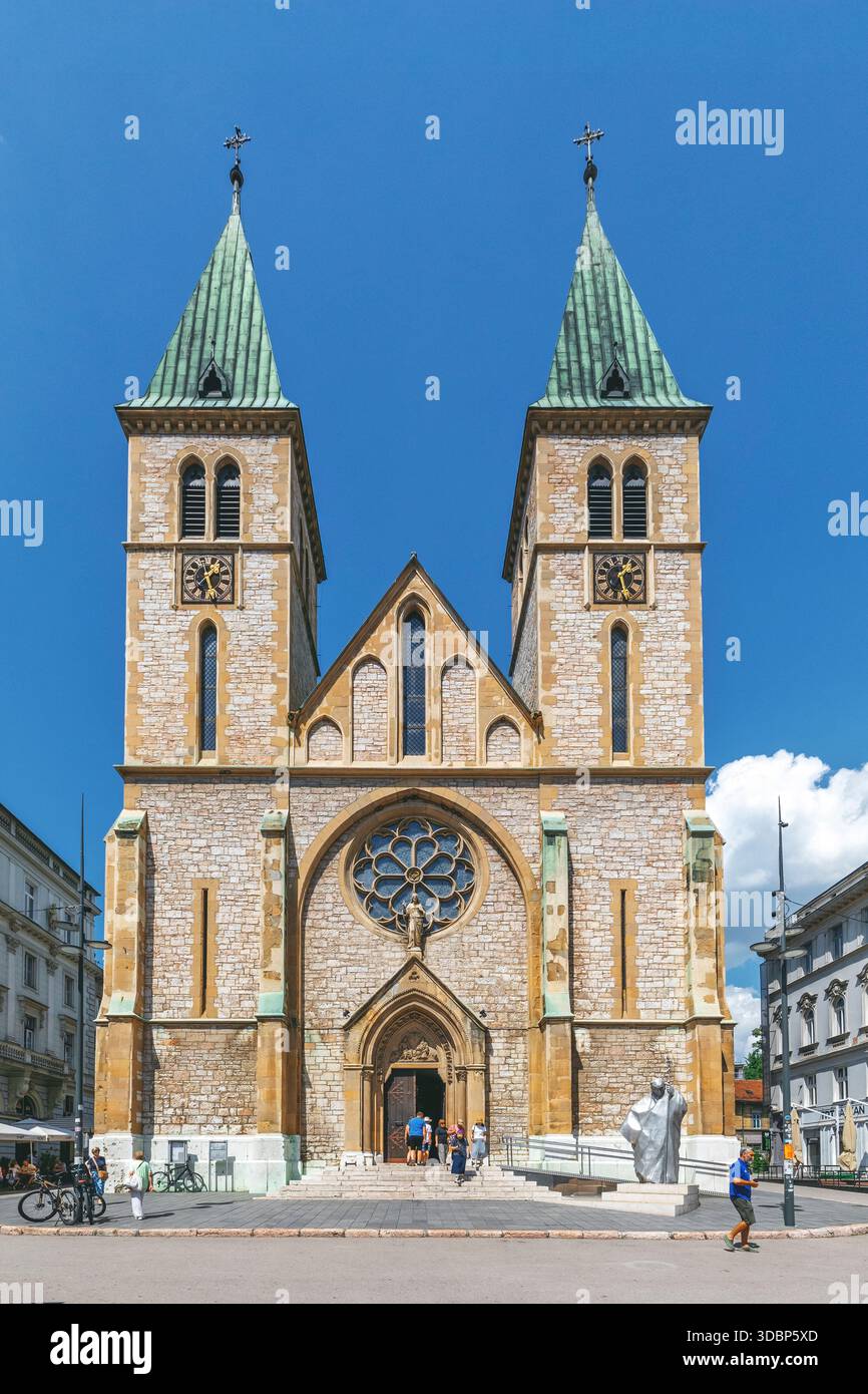 Vista frontale della Cattedrale del Sacro cuore di Sarajevo, Bosnia ed Erzegovina, con le sue torri gemelle e la facciata neogotica sotto un cielo azzurro Foto Stock