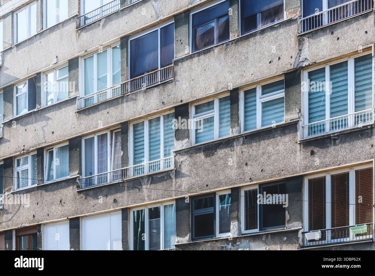Facciata di un edificio lungo Ulica Zmaja od Bosne (Viale dei cecchini) a Sarajevo, che mostra fori proiettili, danni e contrasto architettonico tra finestre e pareti, Sarajevo, Bosnia ed Erzegovina Foto Stock