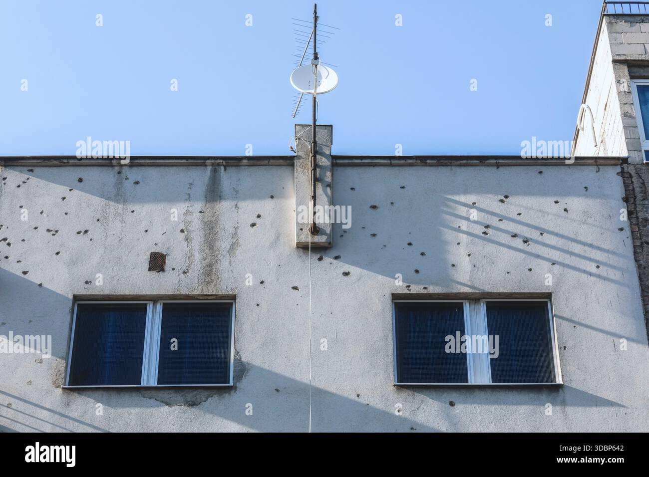 Facciata di un edificio lungo Ulica Zmaja od Bosne (Viale dei cecchini) a Sarajevo, che mostra fori proiettili, danni e contrasto architettonico tra finestre e pareti, Sarajevo, Bosnia ed Erzegovina Foto Stock